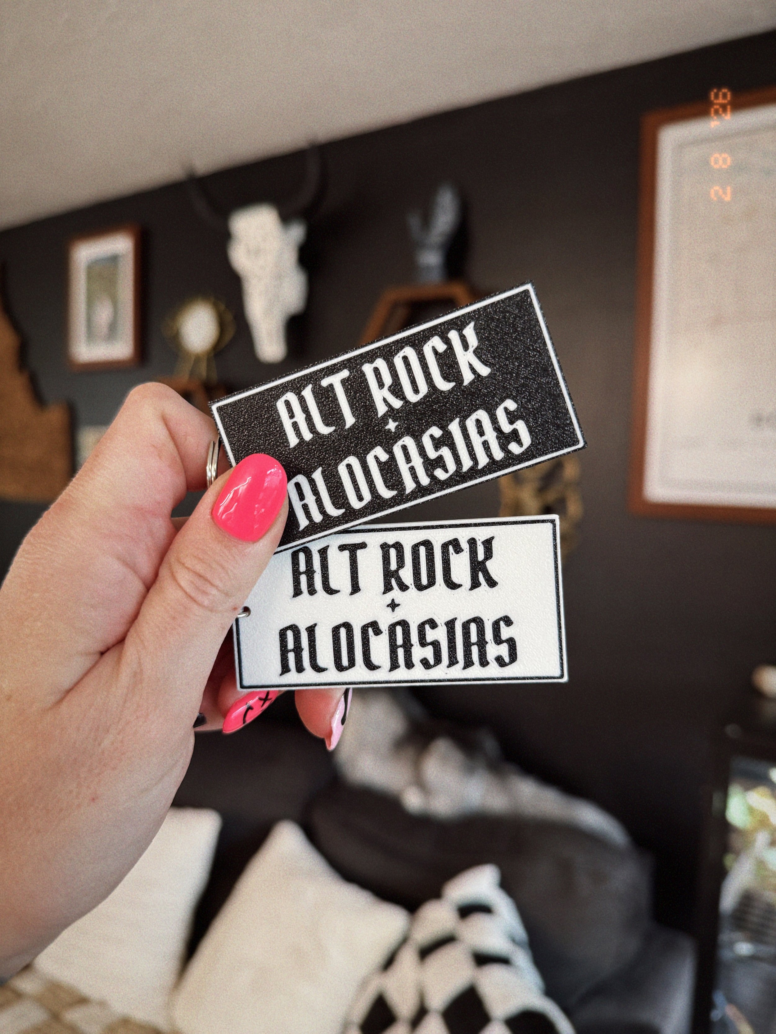 Alt Rock + Alocasias keychains held in hand showing keychain clips and 3D printed texture.