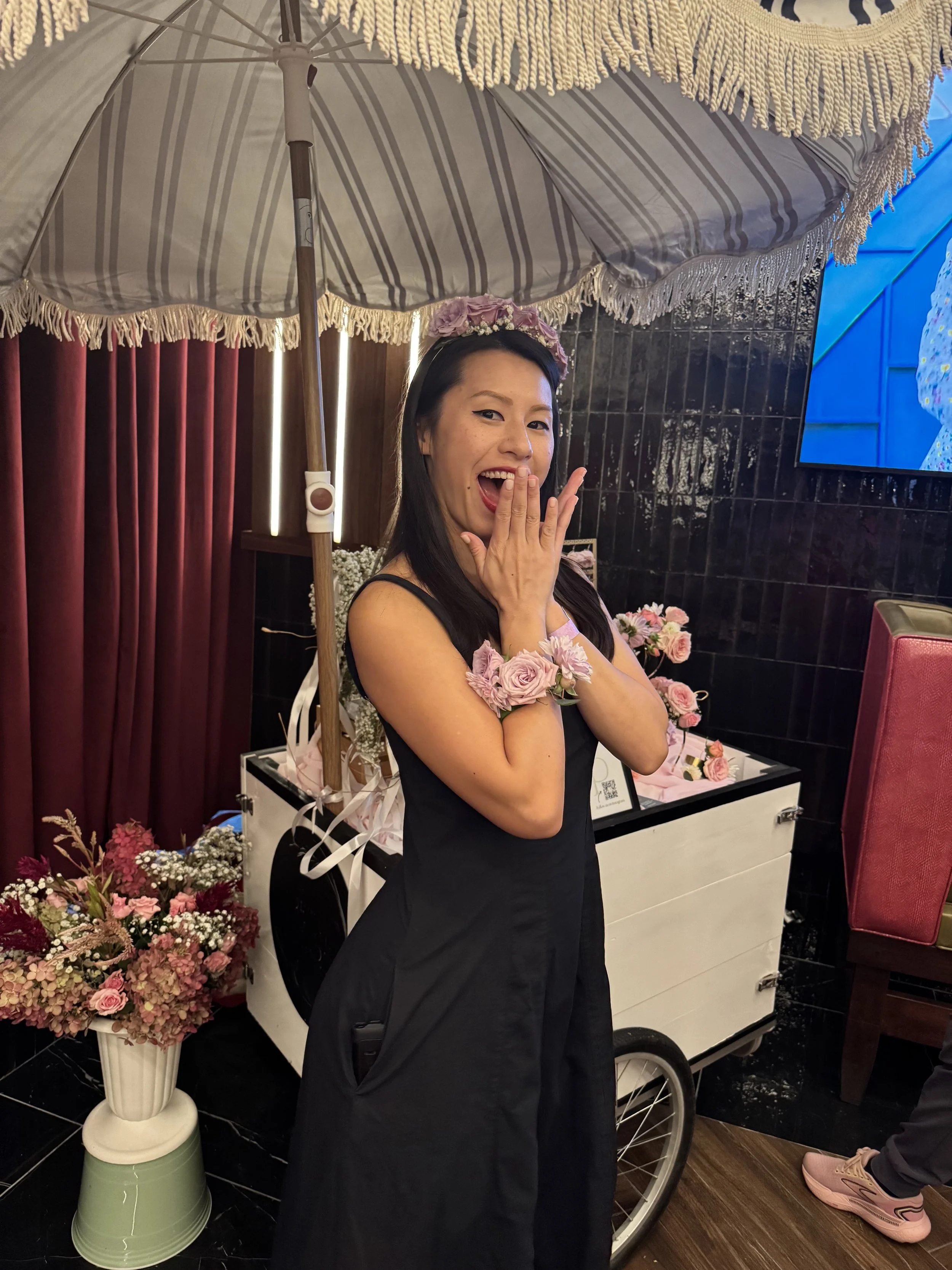 A 20-something person looking excited while wearing a floral corsage and headband