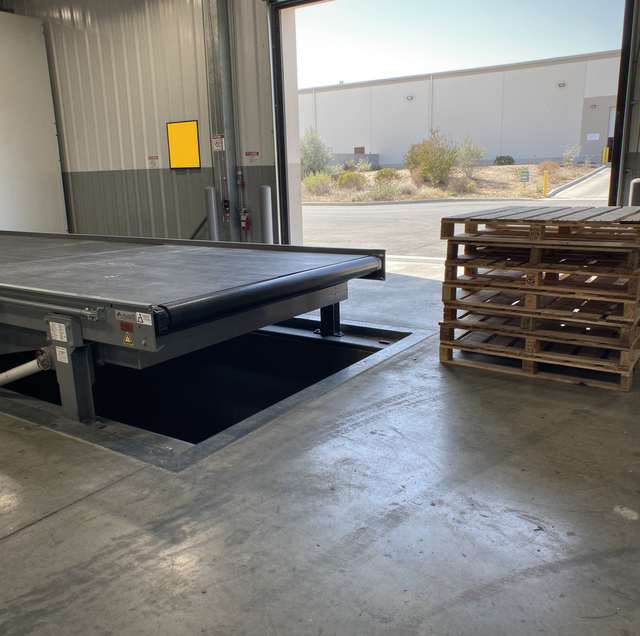Industrial warehouse loading dock with metal platform, wooden pallets, and corrugated metal walls overlooking desert landscap
