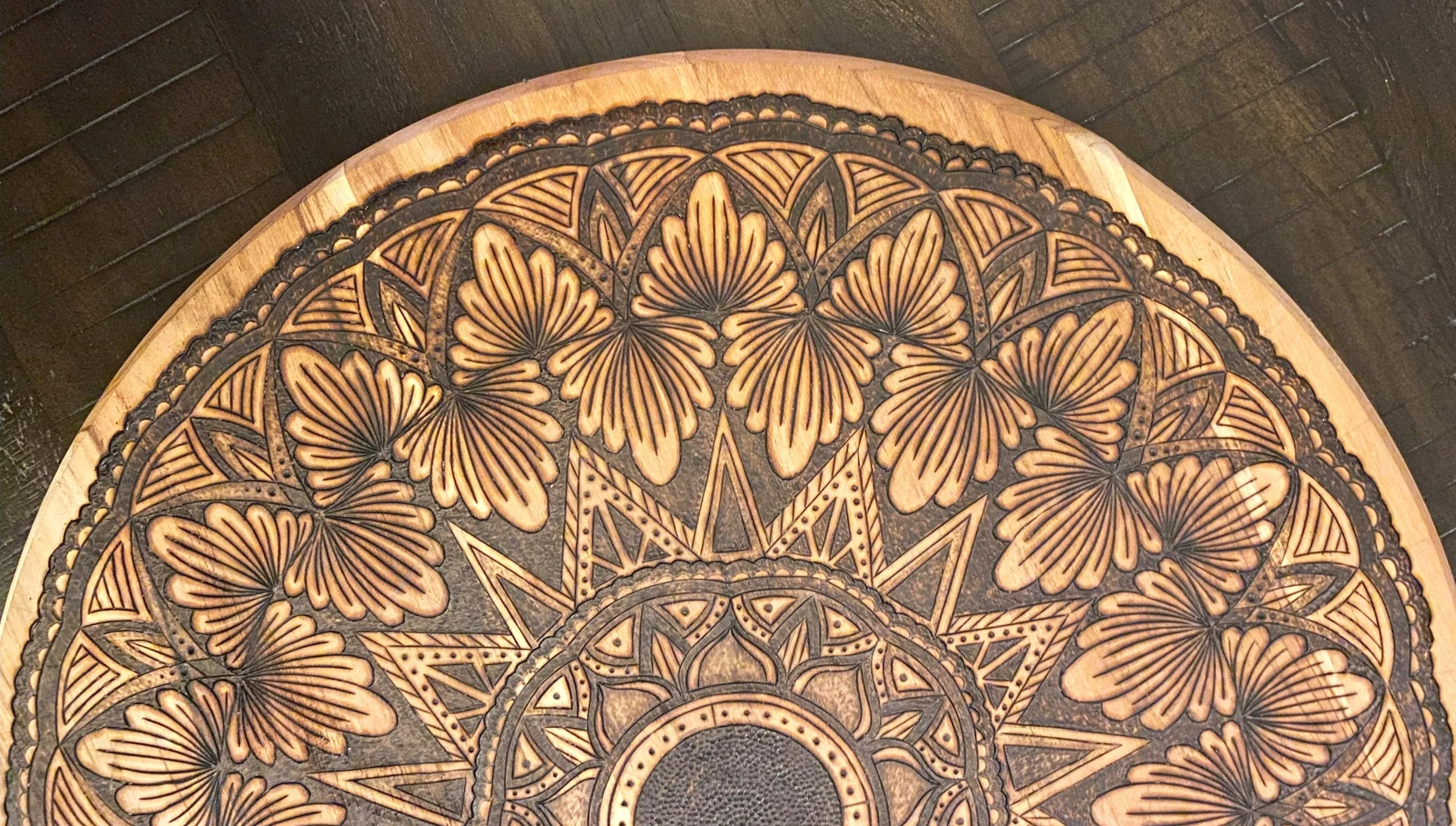 Close-up of a decorative round wooden tray with intricate carved floral and geometric patterns.