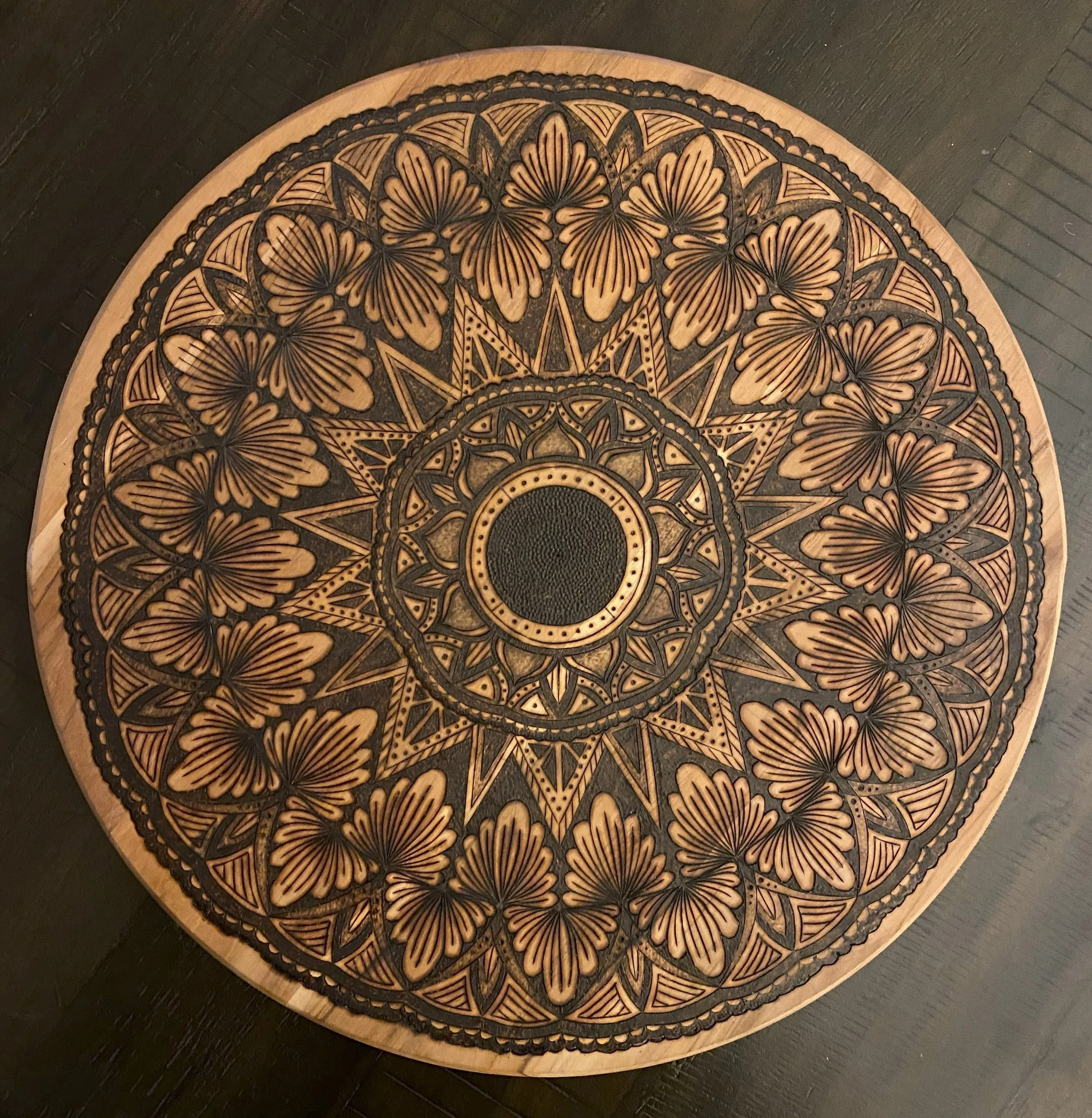 Round wooden table with intricate carved butterfly and geometric patterns, featuring a central circle and repeating motifs in black and wood tones.