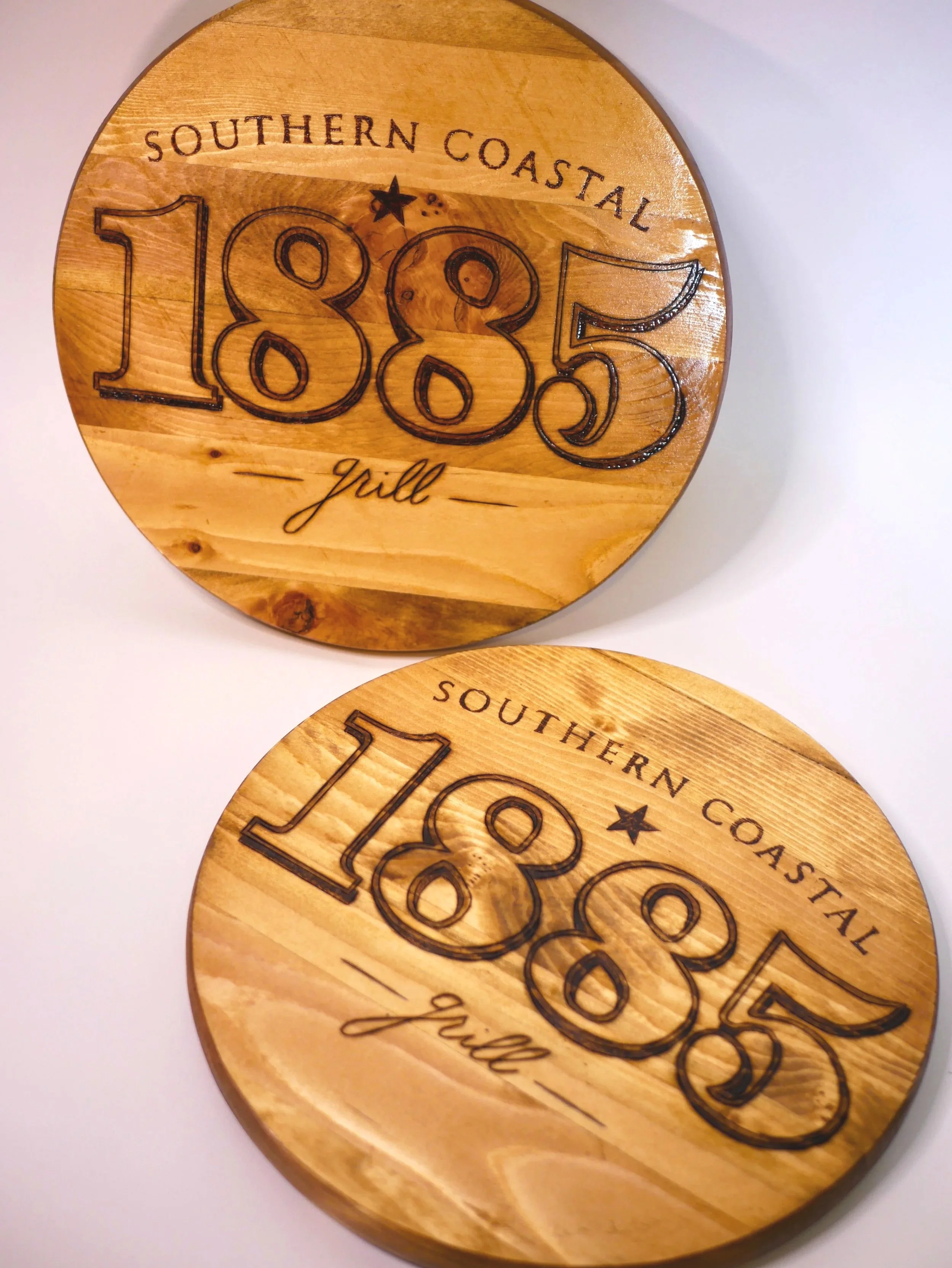 Round wooden signs engraved with 'Southern Coastal 1885 grill' 