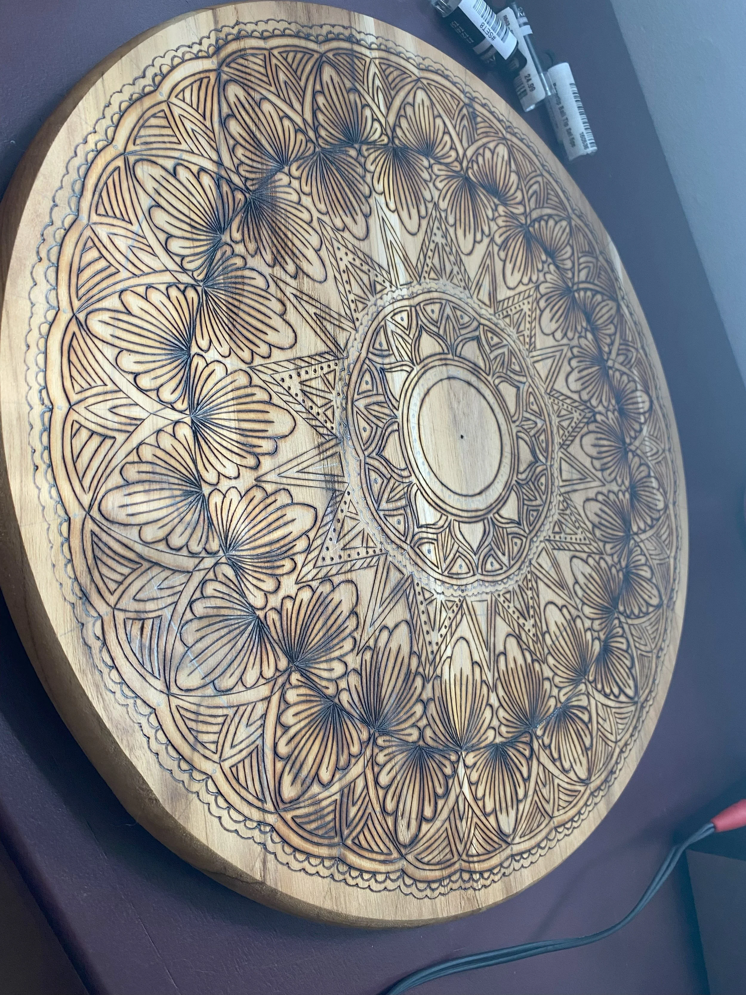 Wooden round table with intricate mandala and butterfly carvings.