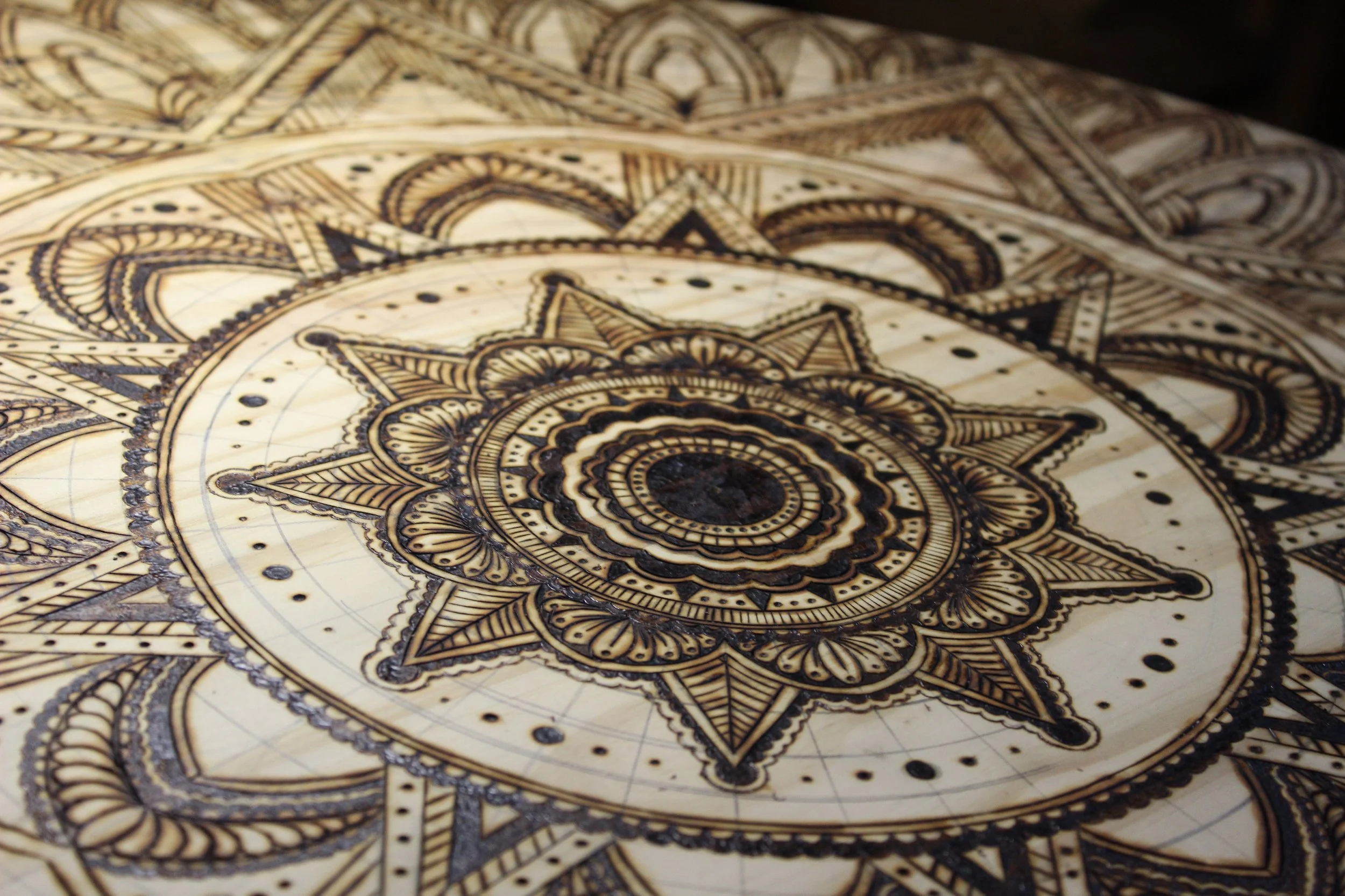 Decorative wooden puzzle piece with intricate mandala and geometric patterns burned into the surface.