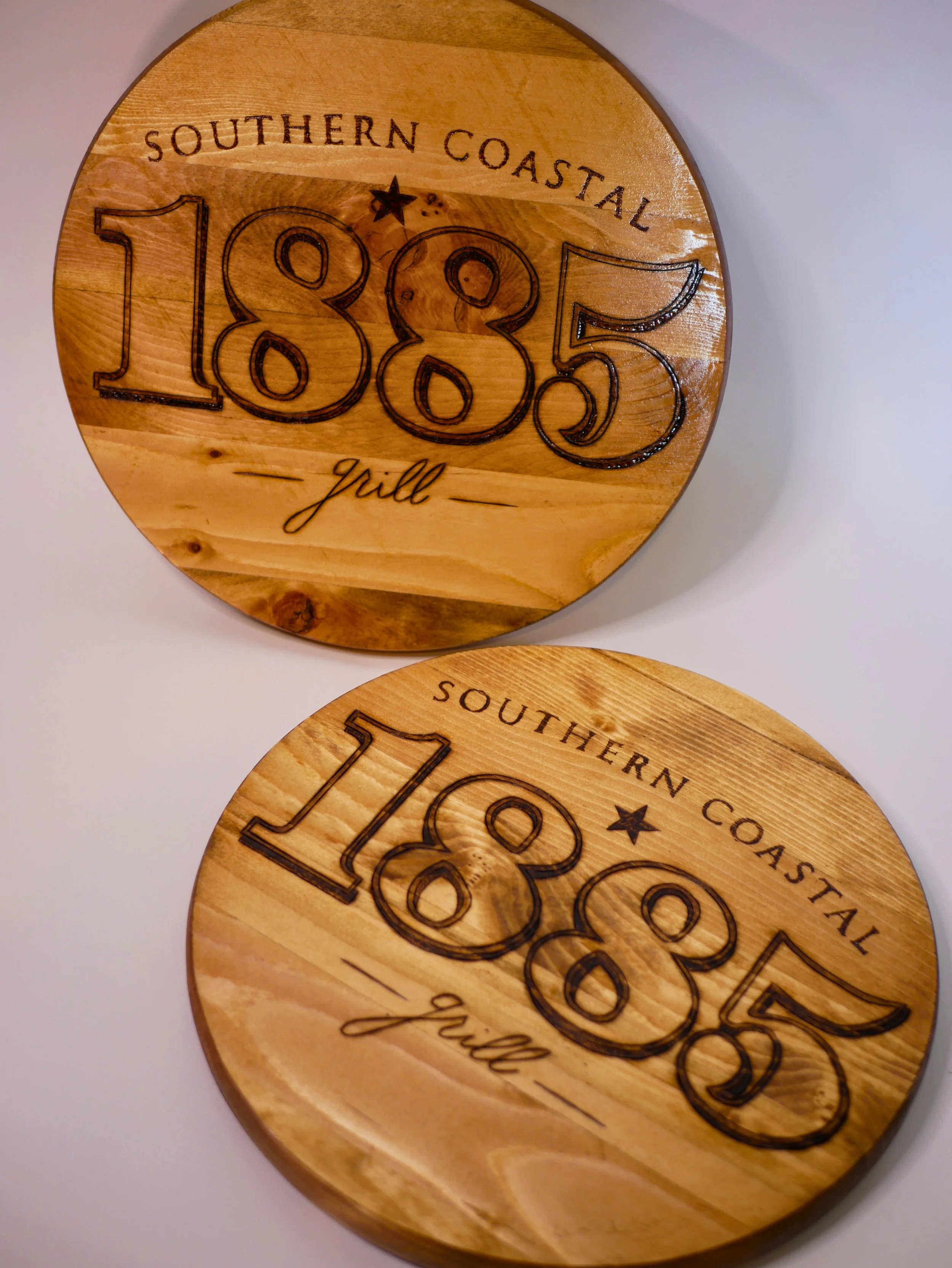 Round wooden signs engraved with 'Southern Coastal 1885 grill' 