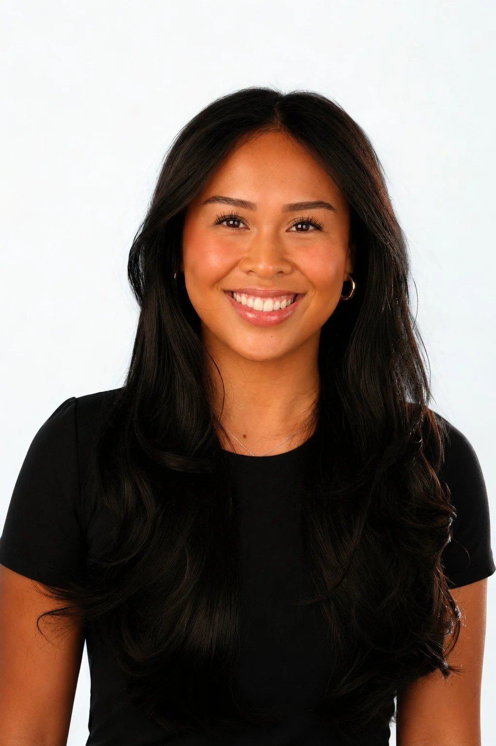 A smiling woman with long black hair, wearing a black top and hoop earrings, against a white background.