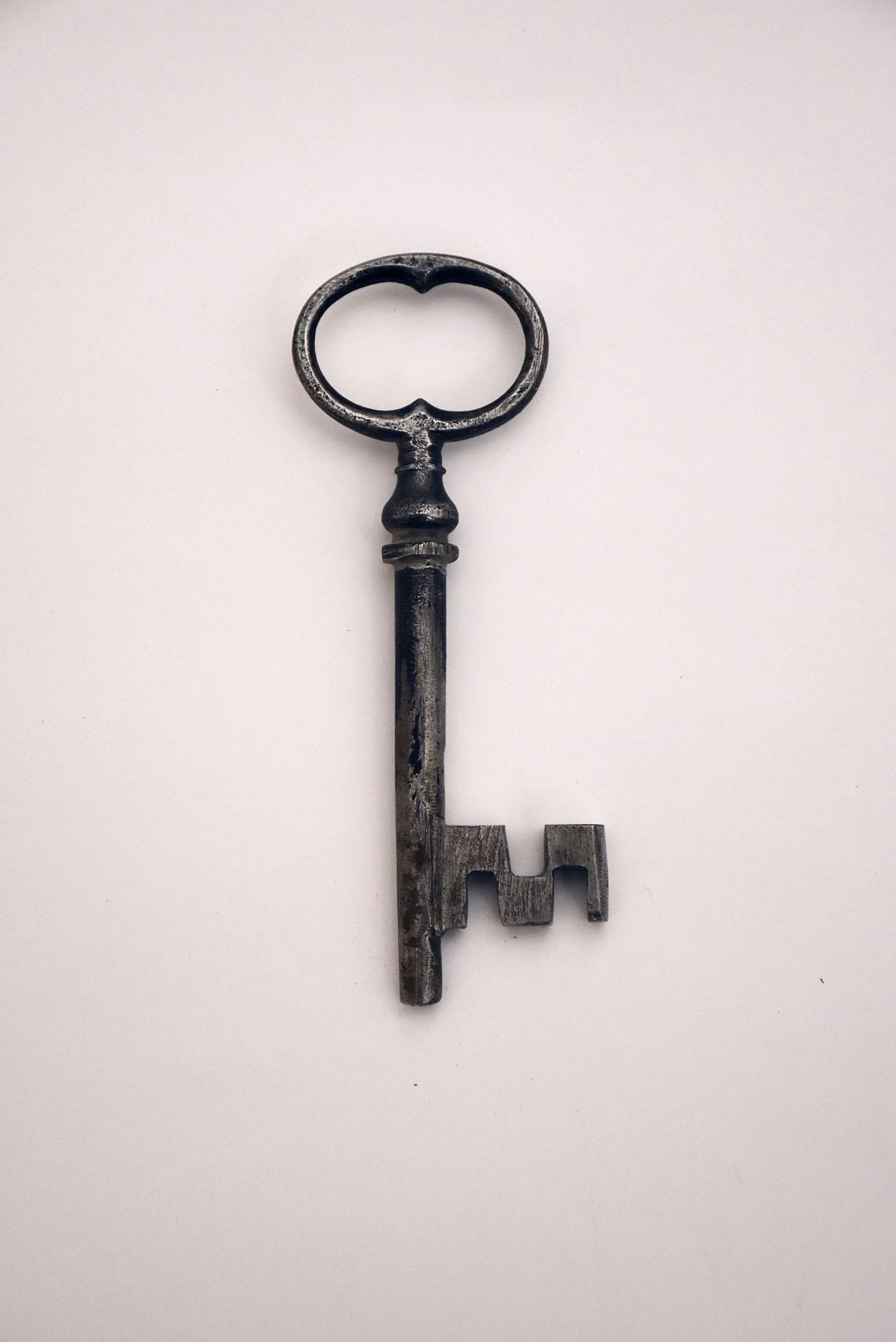 An old, rusty skeleton key on a white background.