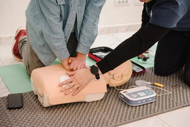Close-up of hands performing chest compressions on a CPR training manikin.