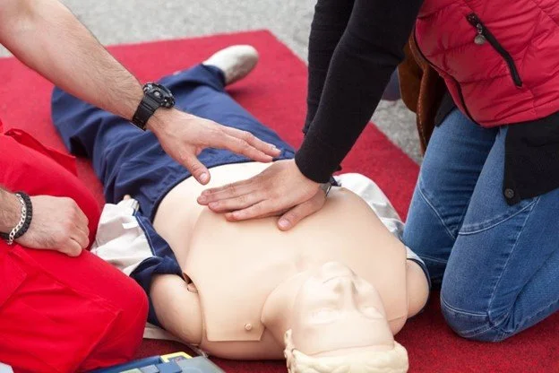 Instructor demonstrating CPR compressions on a training manikin during a first aid course.