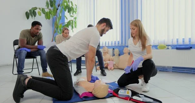 Participant practicing chest compressions on a CPR manikin in a training session.