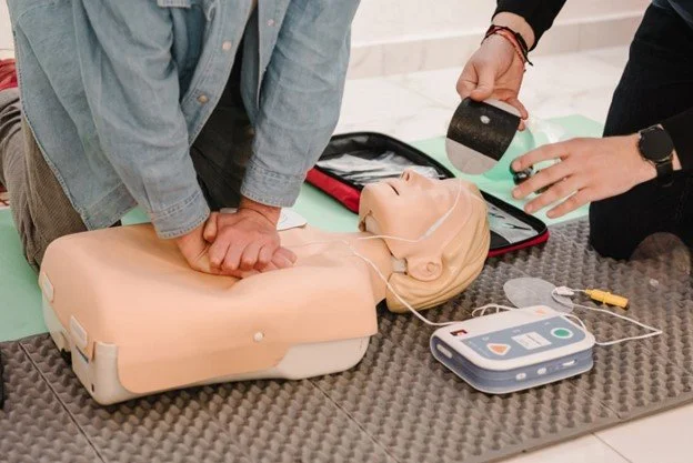 Student practicing rescue breaths on a CPR manikin under supervision.