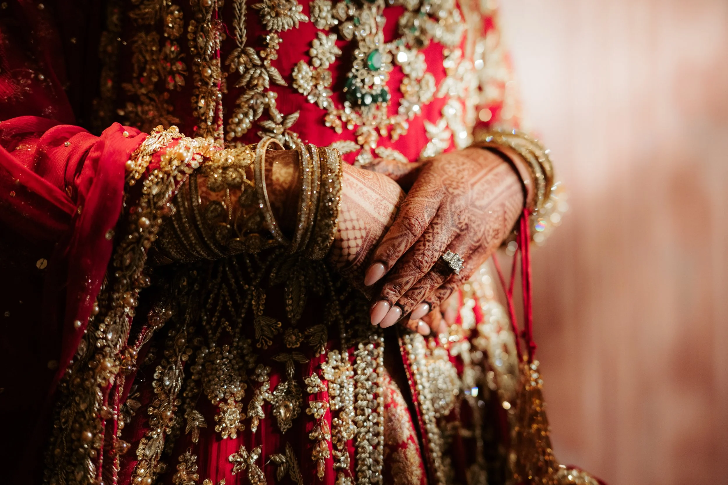 Pakistani Bridal henna in on a red lengha at baltimore waterfront wedding captured by snkworks with warm lighting and romantic mood