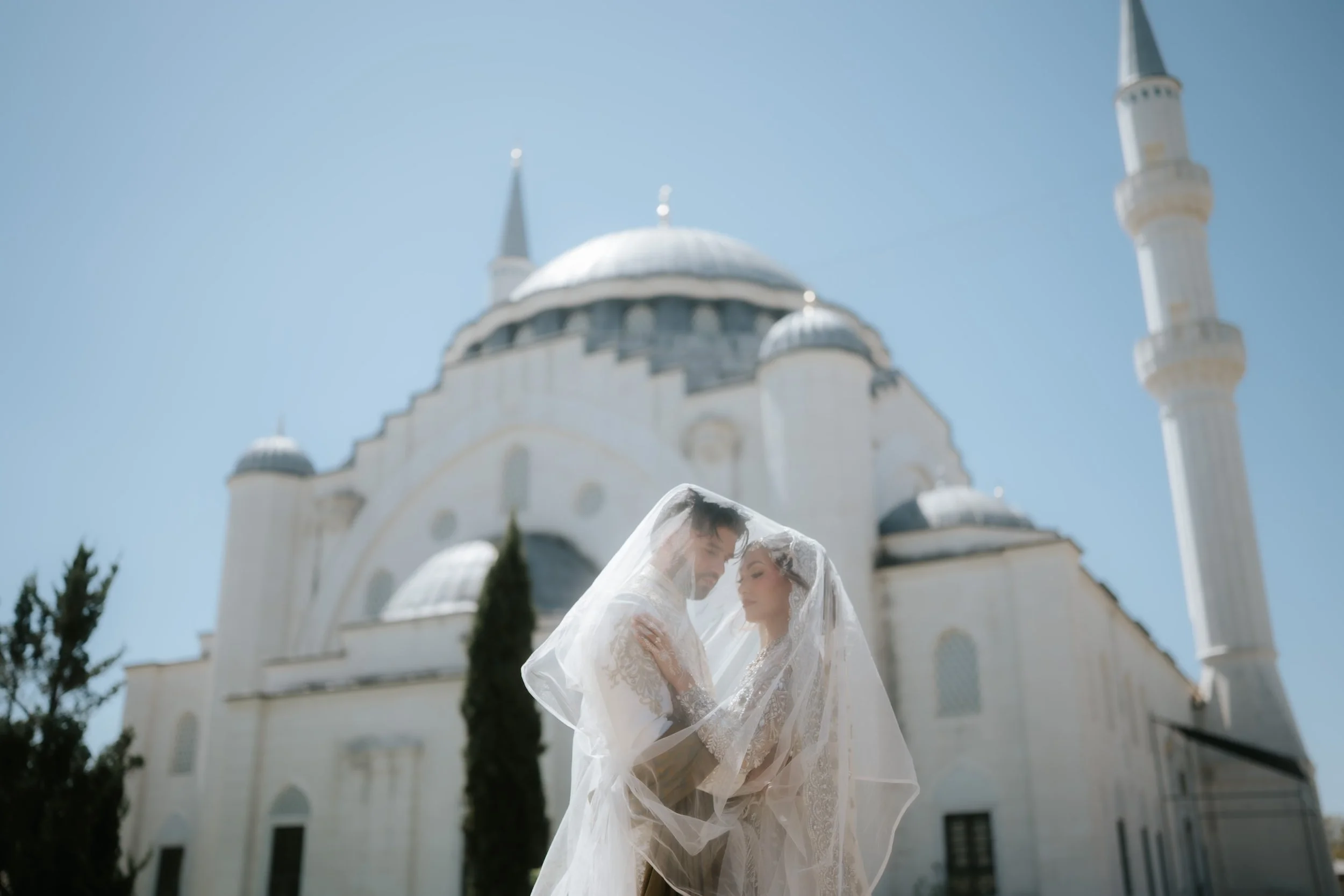 Bride and Groom at Diyanet Center of America on thieir Nikah day with masjid in the background under her wedding veil