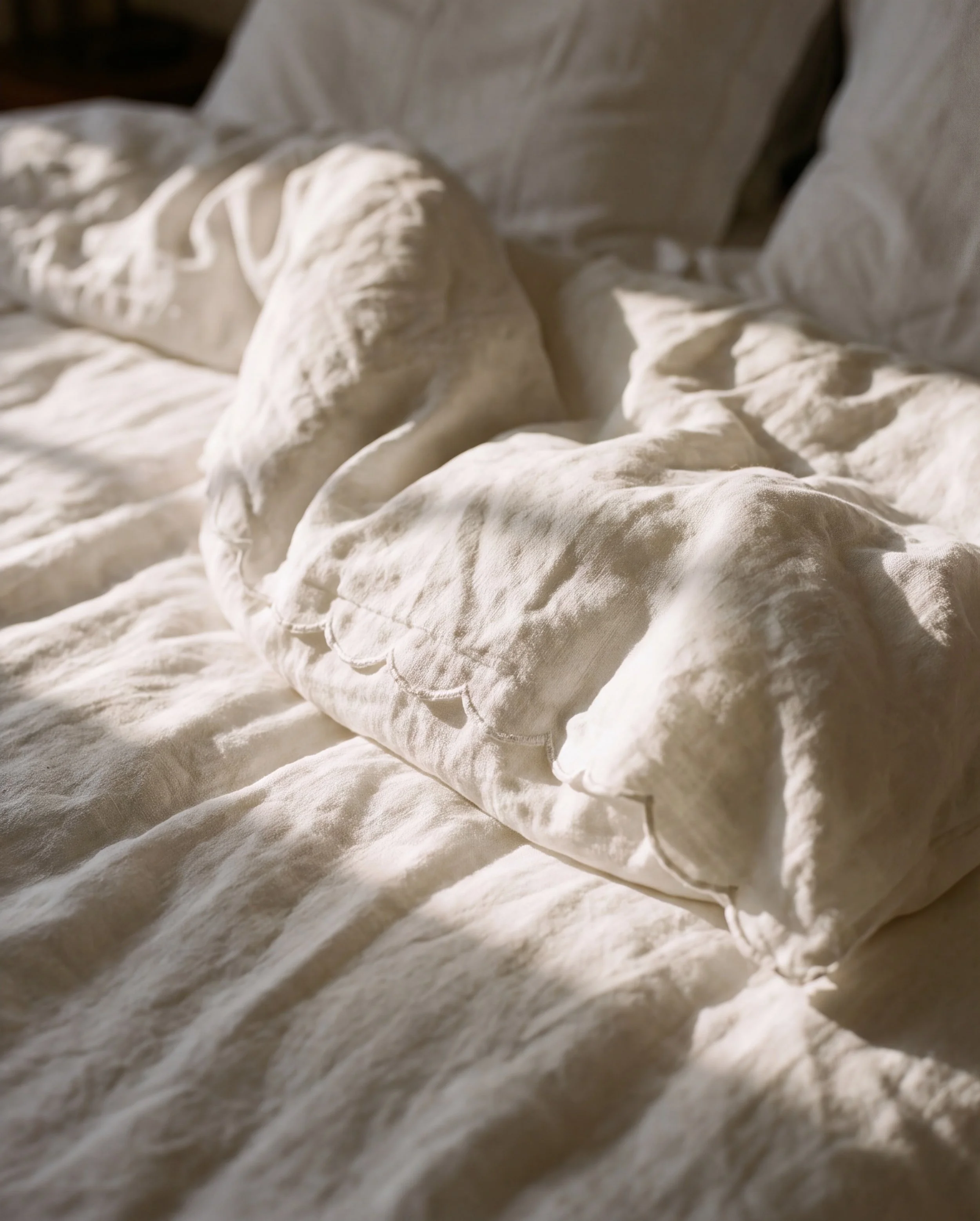 Close-up of crumpled, cream-colored fabric with soft lighting and shadows.