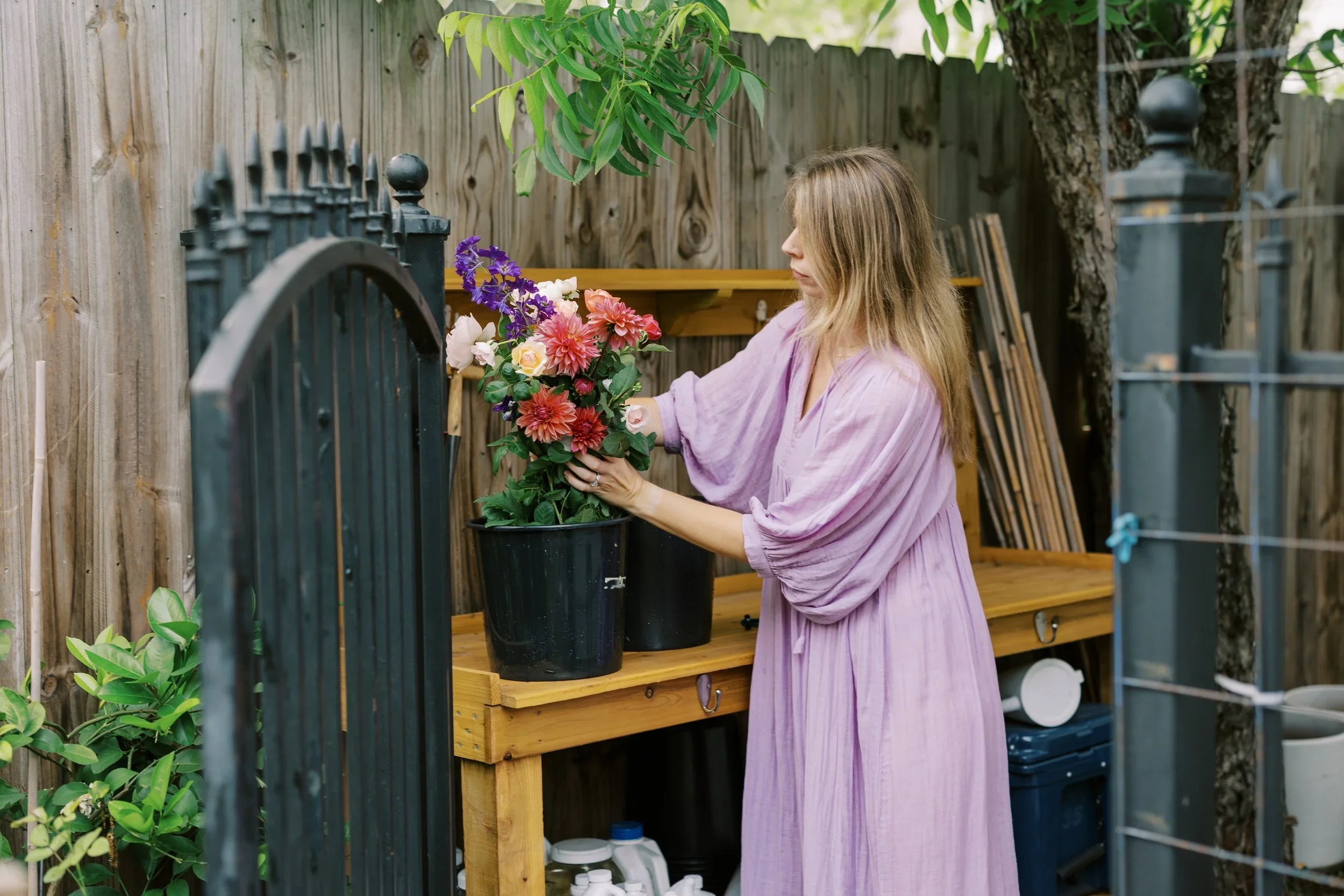 Alex arranging a mixed cut flower bouquet with roses at a garden table, representing the Garden Rose Crash Course.