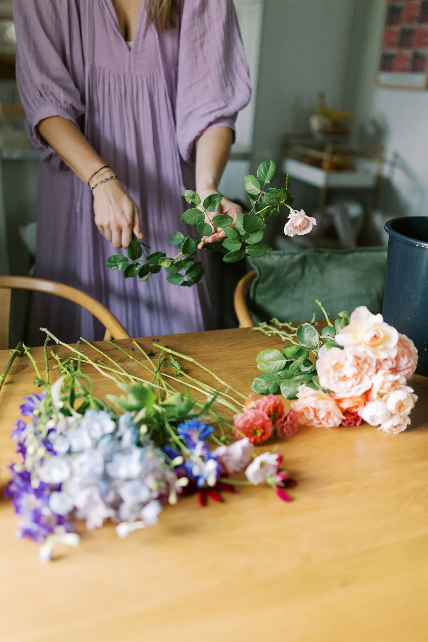 Alex trimming flowers and roses on a table at Bungalow Blooms flower farm in Houston.