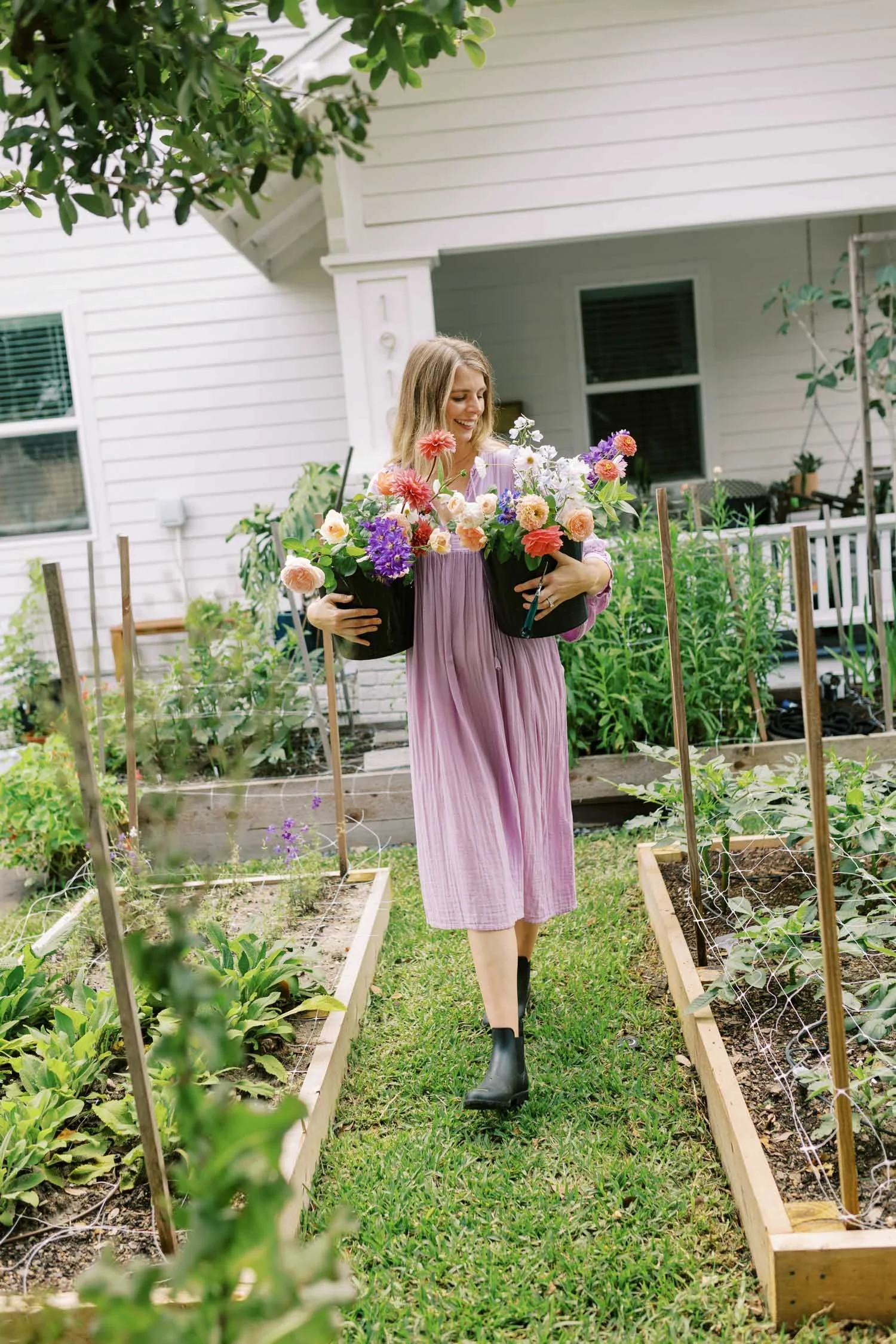 Alex holding buckets of colorful cut flowers and roses at her Houston flower farm.
