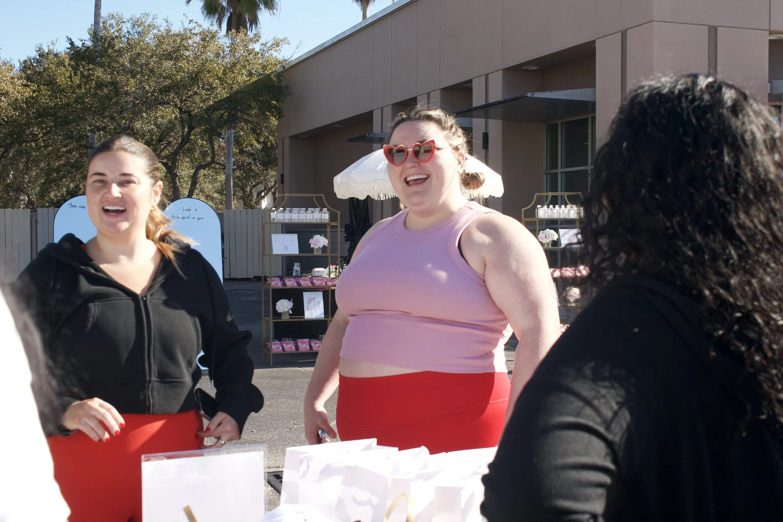 lady in pink and red athletic wear with heart shaped sunglasses, smiling