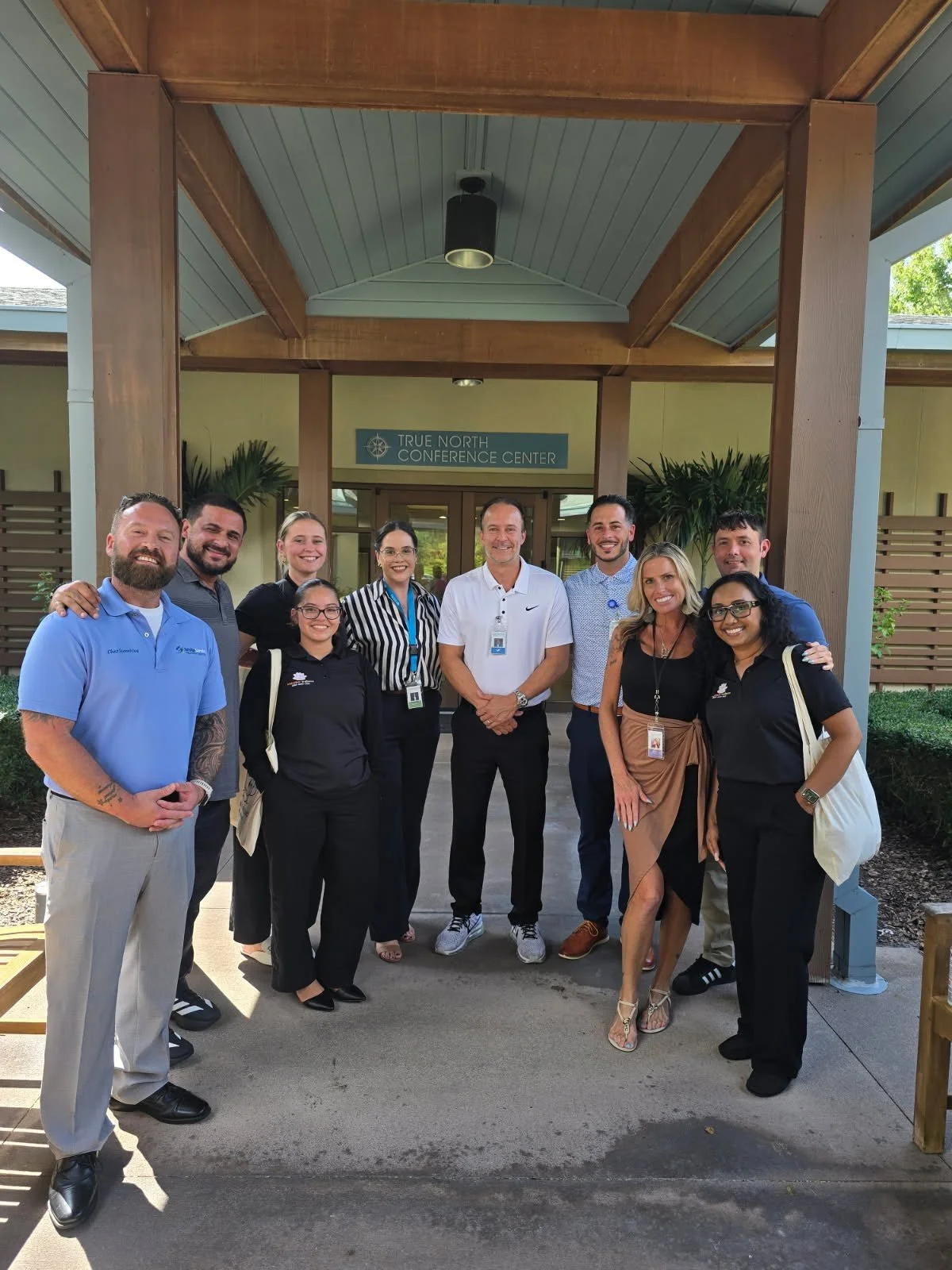 Group of ten people standing in front of the True North Conference Center, smiling for a group photo.