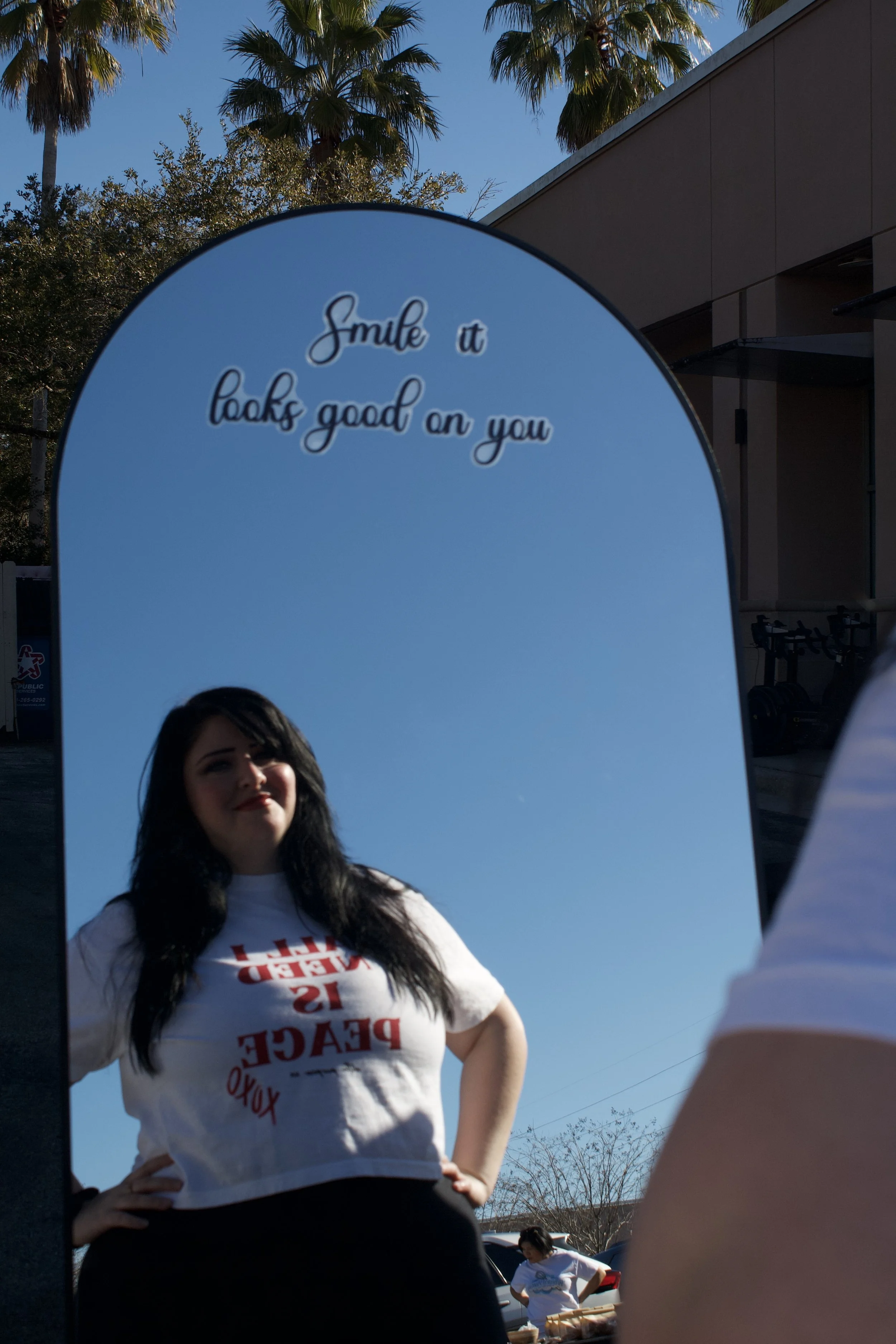 photo of a lady looking into a mirror that says "smile, it looks good on you"