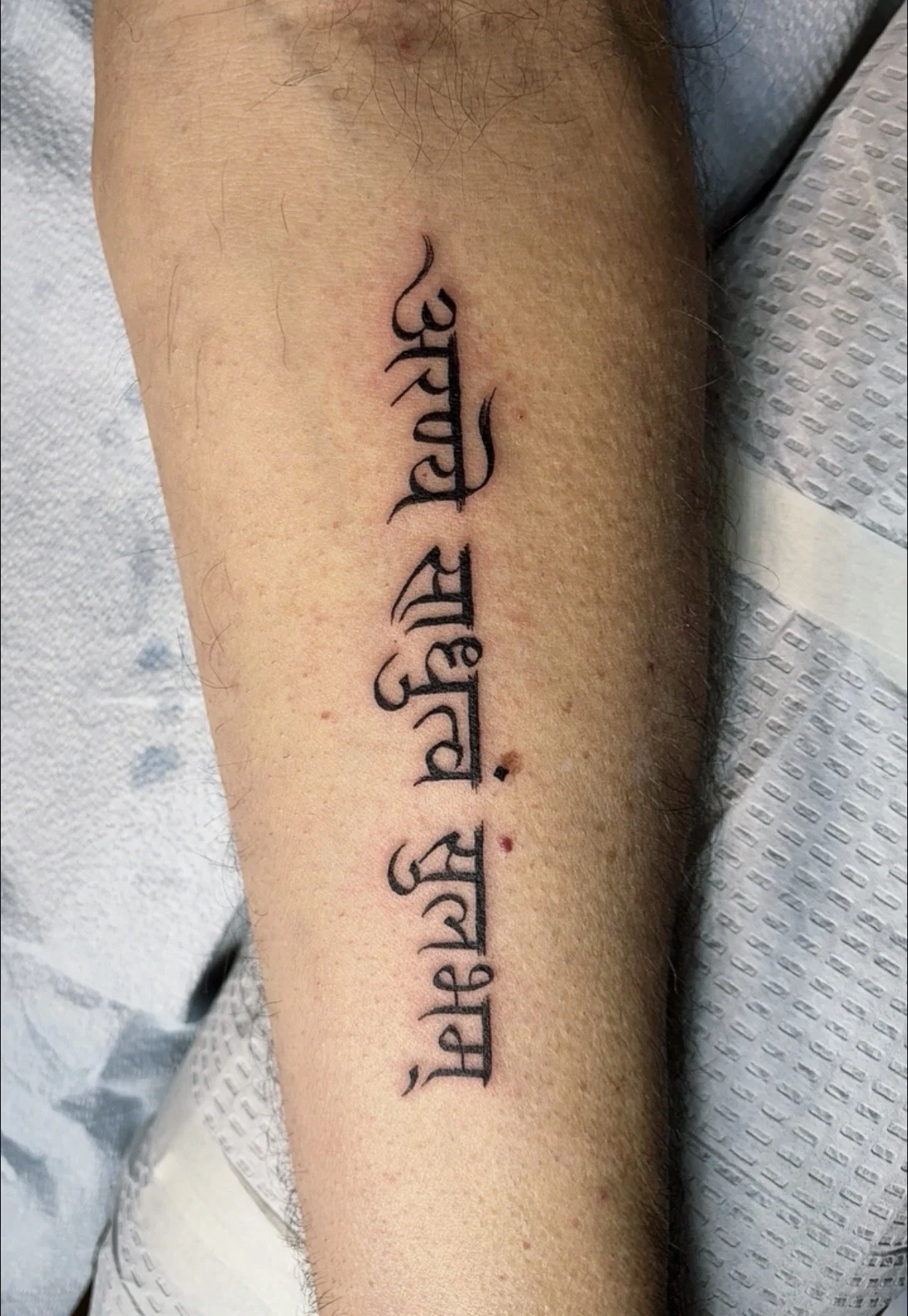 Tattoo with words written in a Hindi font on a person's inner forearm.