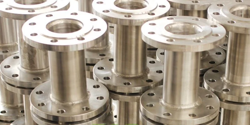 Multiple metal industrial flanges stacked together in a manufacturing setting.