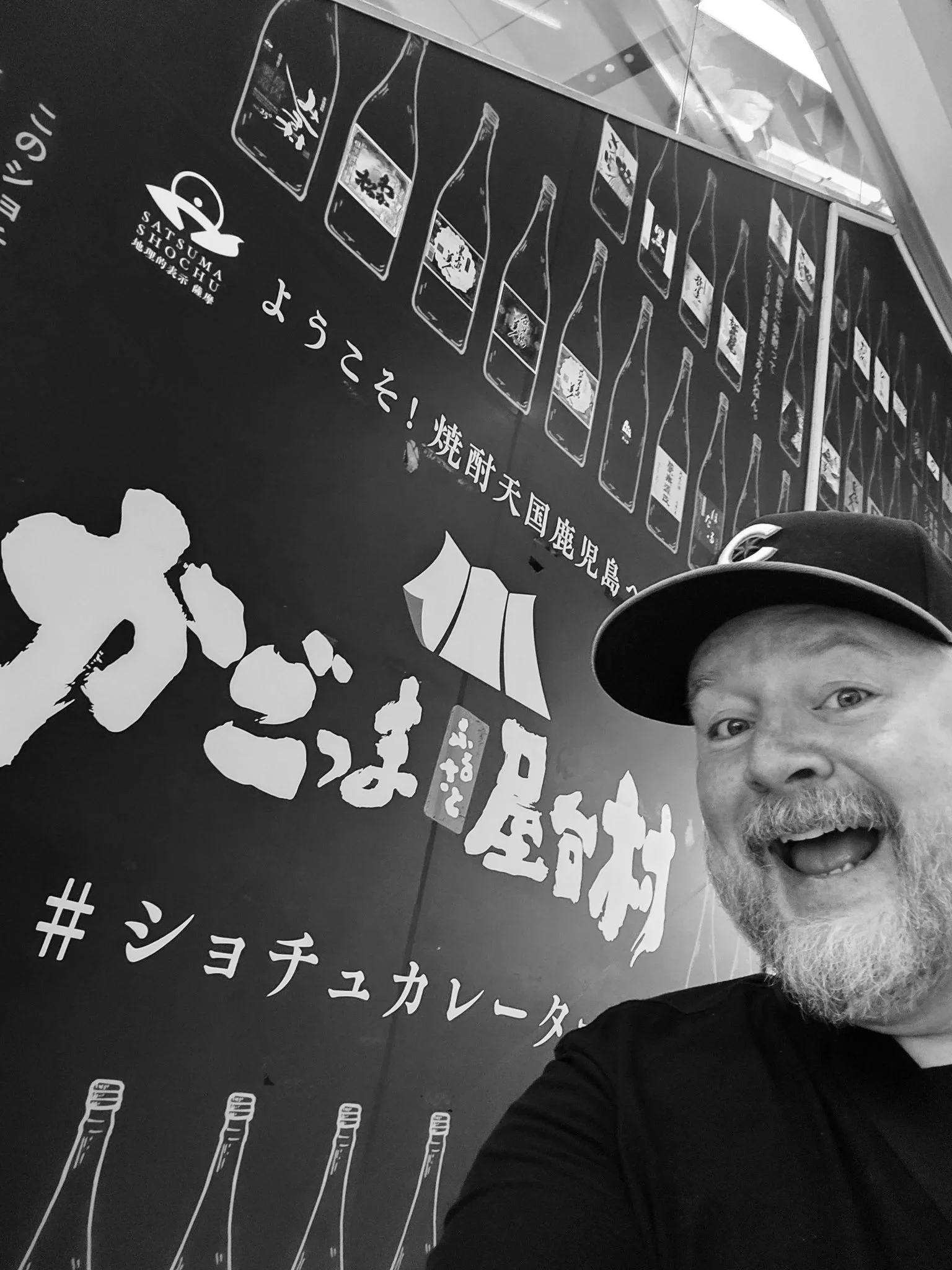 Mike in Kagoshima in front of a wall celebrating local shochu