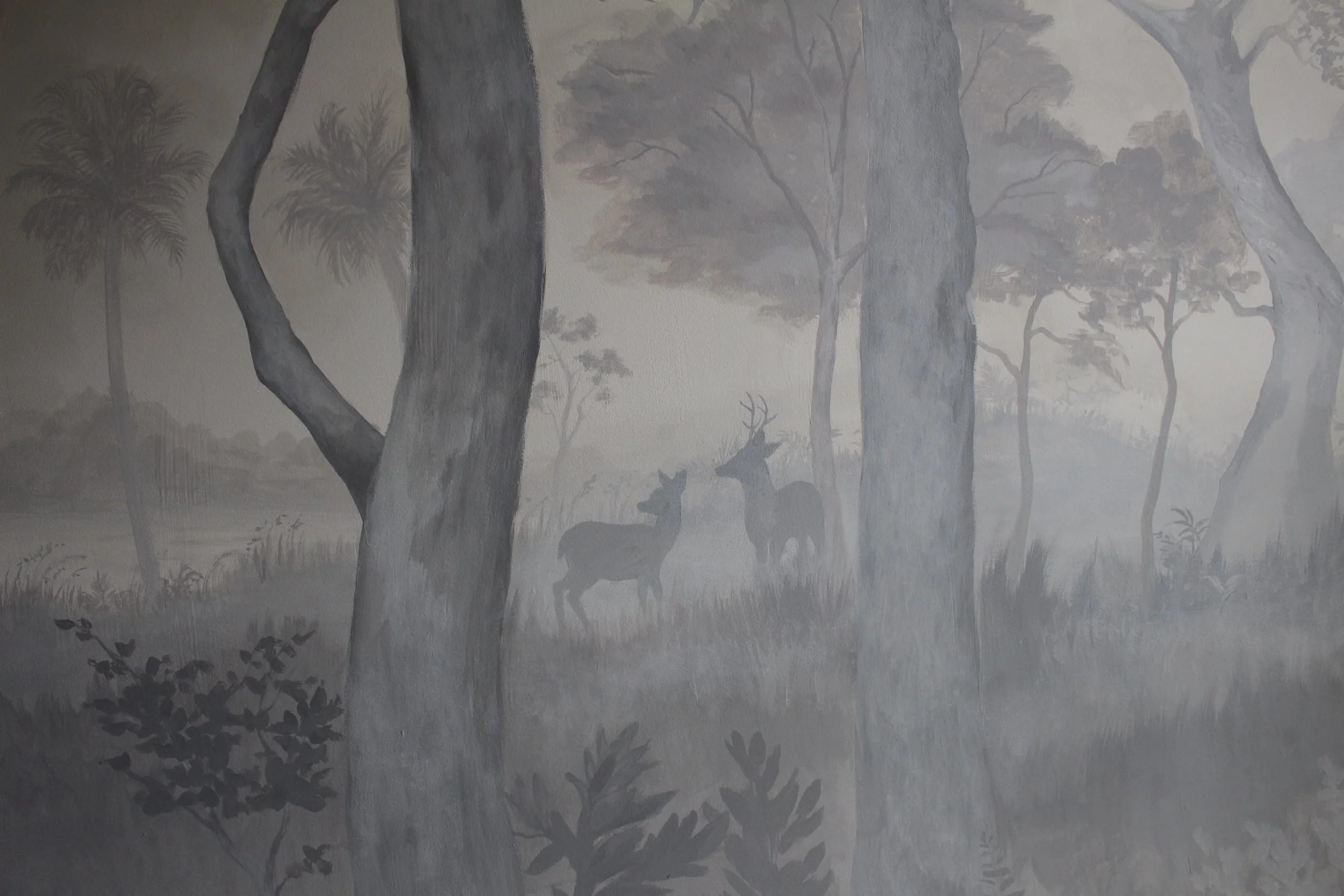 A black and white mural of a foggy forest scene with trees and two deer in the background by fine art muralist Gabrielle Hasenstab.