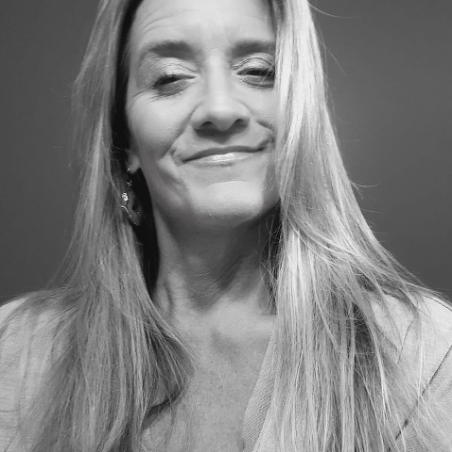Black and white photo of a woman with long hair, smiling with eyes closed.