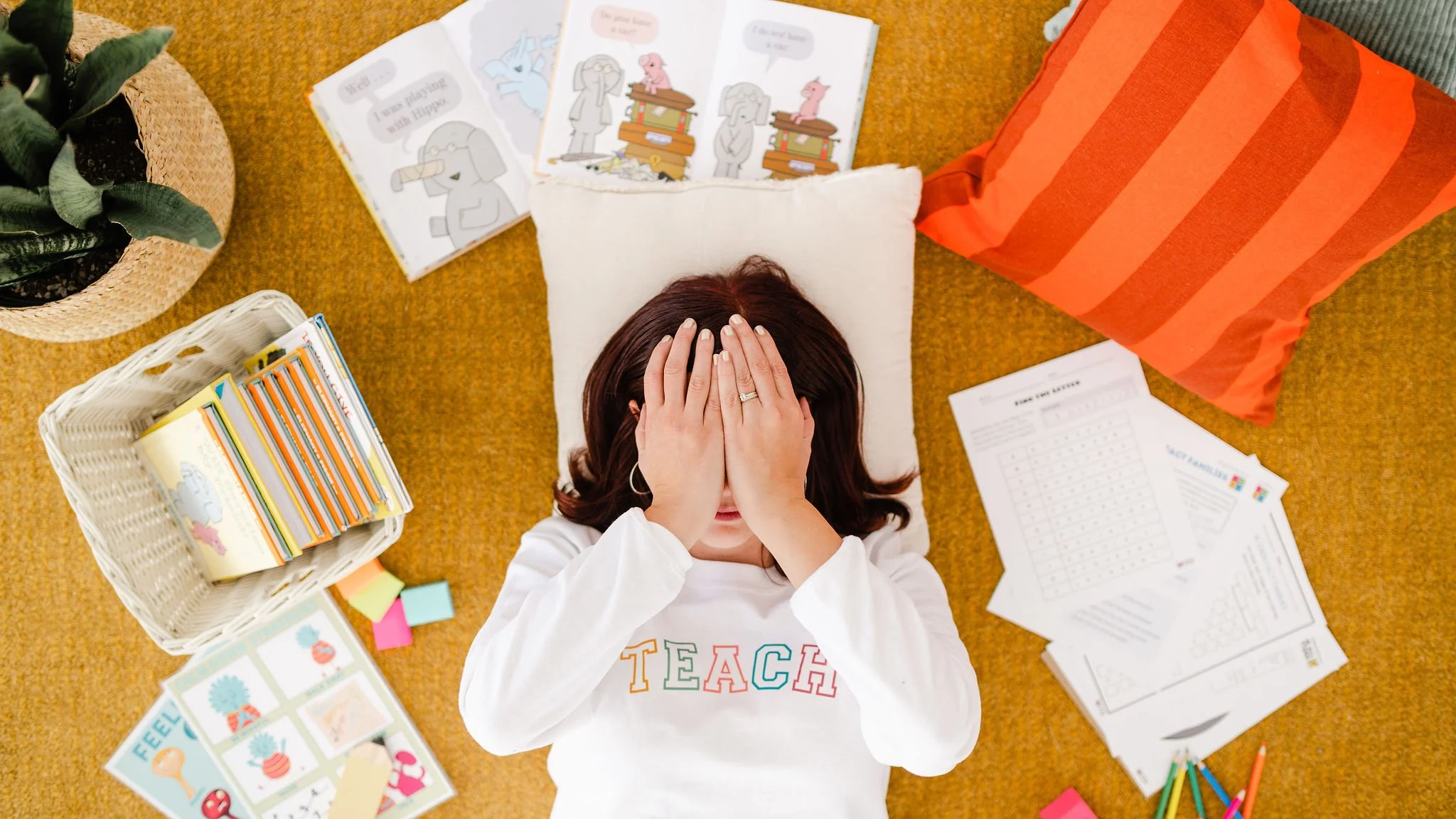 Female teacher laying on a pillow with hands over her face in embarrassment.