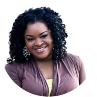 Portrait of a woman with curly hair smiling, wearing earrings and a mauve top.