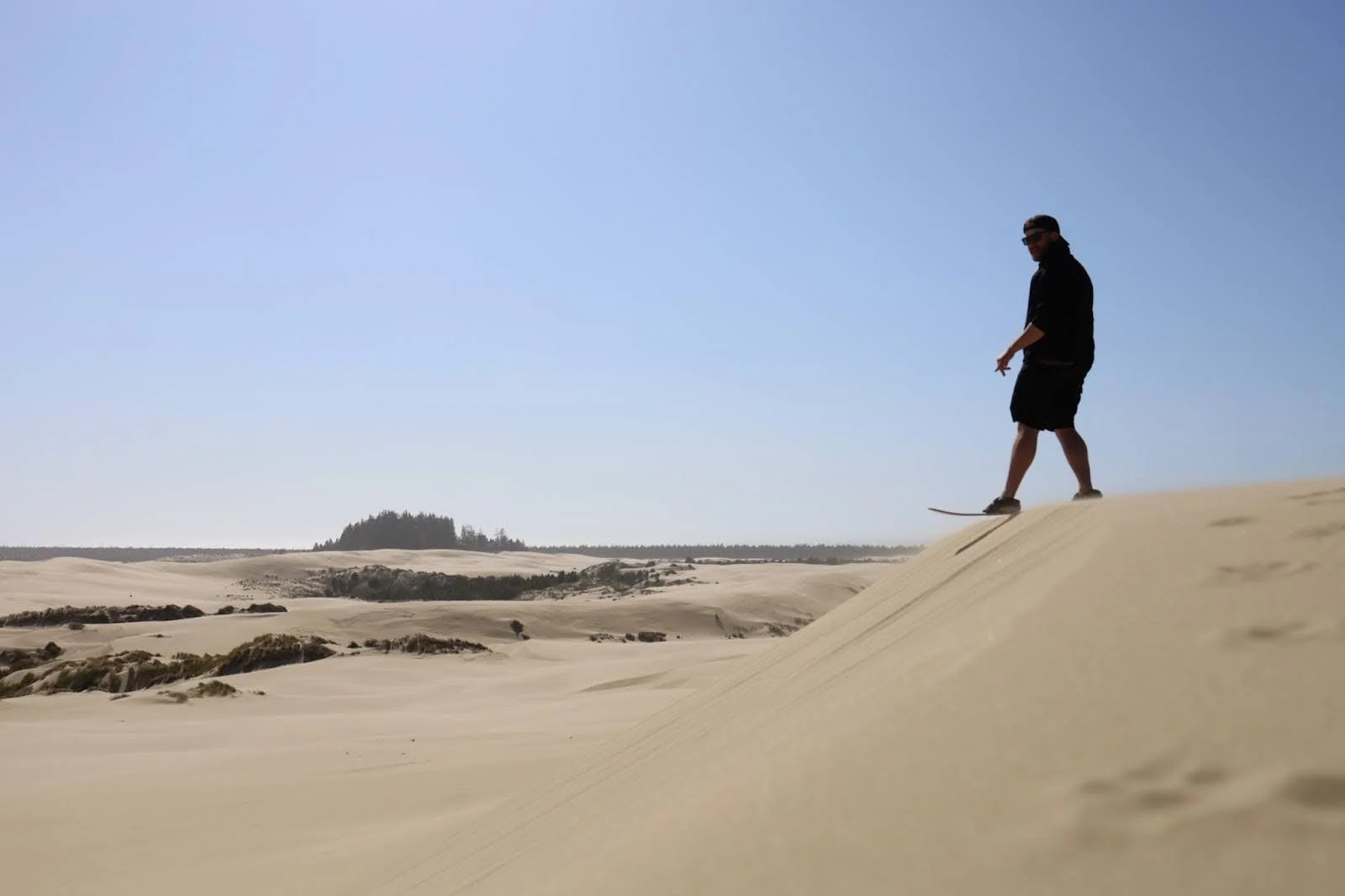 A sandboarder prepares to drop into a dune on the Oregon coast.