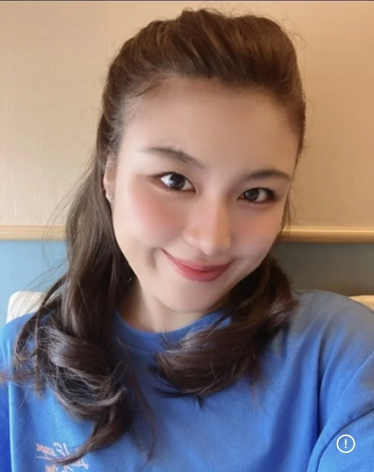 Woman holding white pumpkin at pumpkin patch with many orange pumpkins around her.