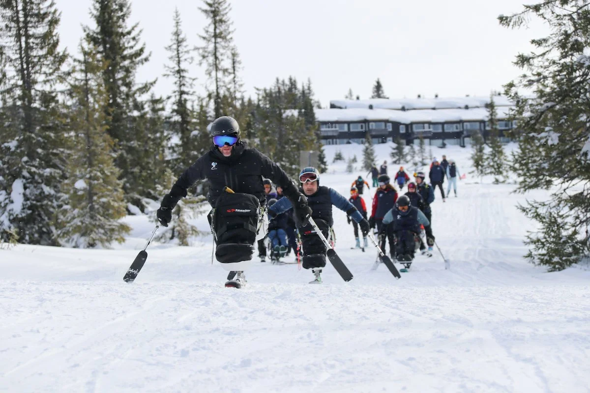 Person på snødekt fjelltopp med ski, utsikt over snødeide landskap og skymot sunrise eller sunset.