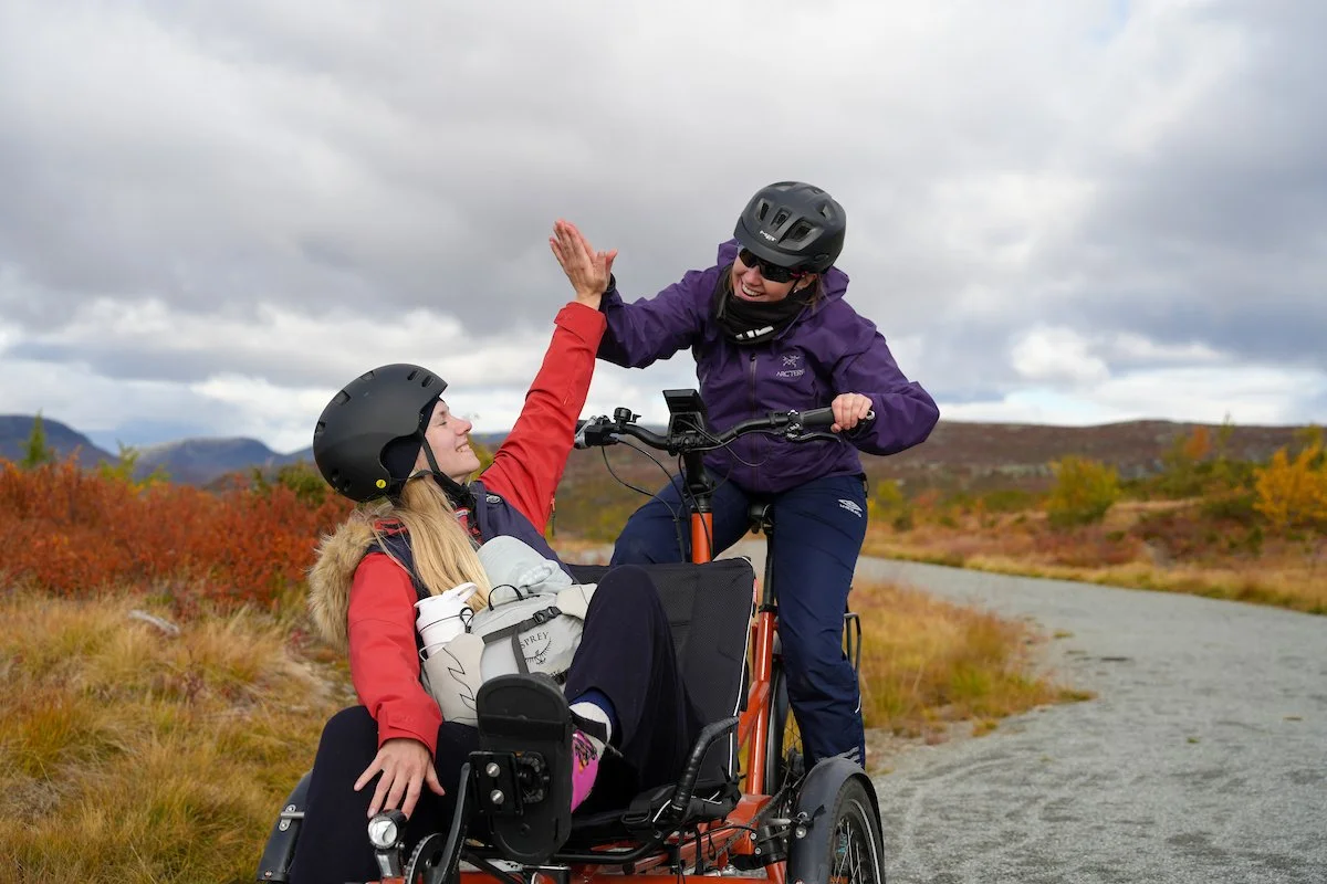 En ung person i hjelm sykler på en grusvei i en skog.