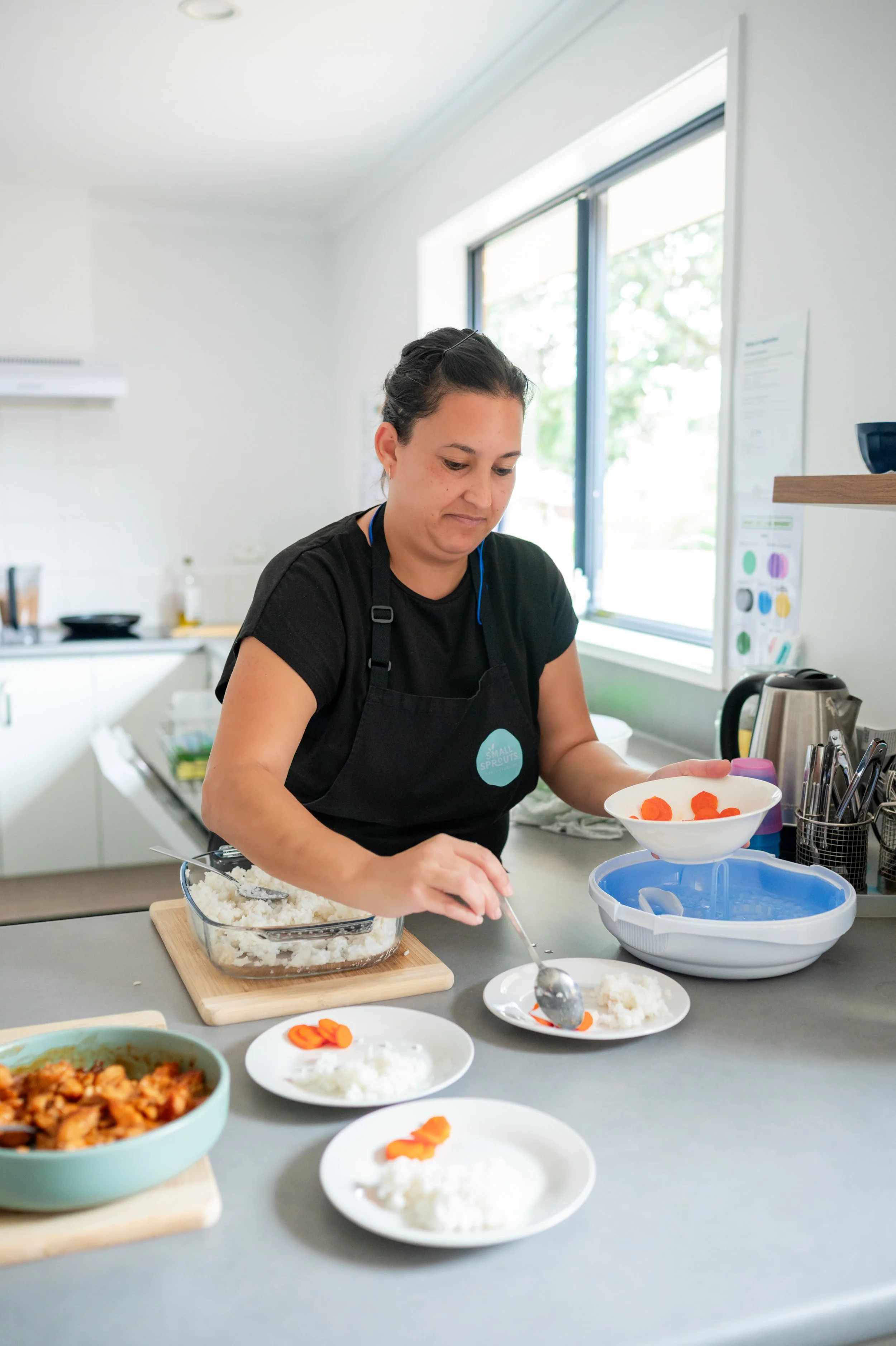 Simone our Kai Creator plating rice and carrots for our little Sprouts in Whangaparaoa