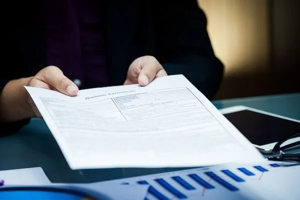 2 hands holding an offer paper and submitting it