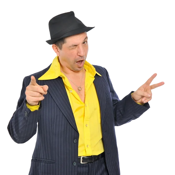 Ein humorvoller Mann trägt einen schwarzen Hut, eine gelbe Hemd und eine dunkle, gestreifte Jacke. Er macht eine Handbewegung, winkt mit zwei Fingern und hat einen schelmischen Gesichtsausdruck.