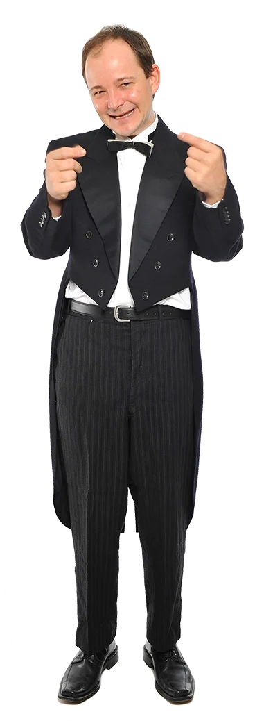 Ein komödiantischer Mann trägt einen Smoking und posiert mit einem breiten Lächeln, zeigt auf sich selbst und sieht glücklich aus.
