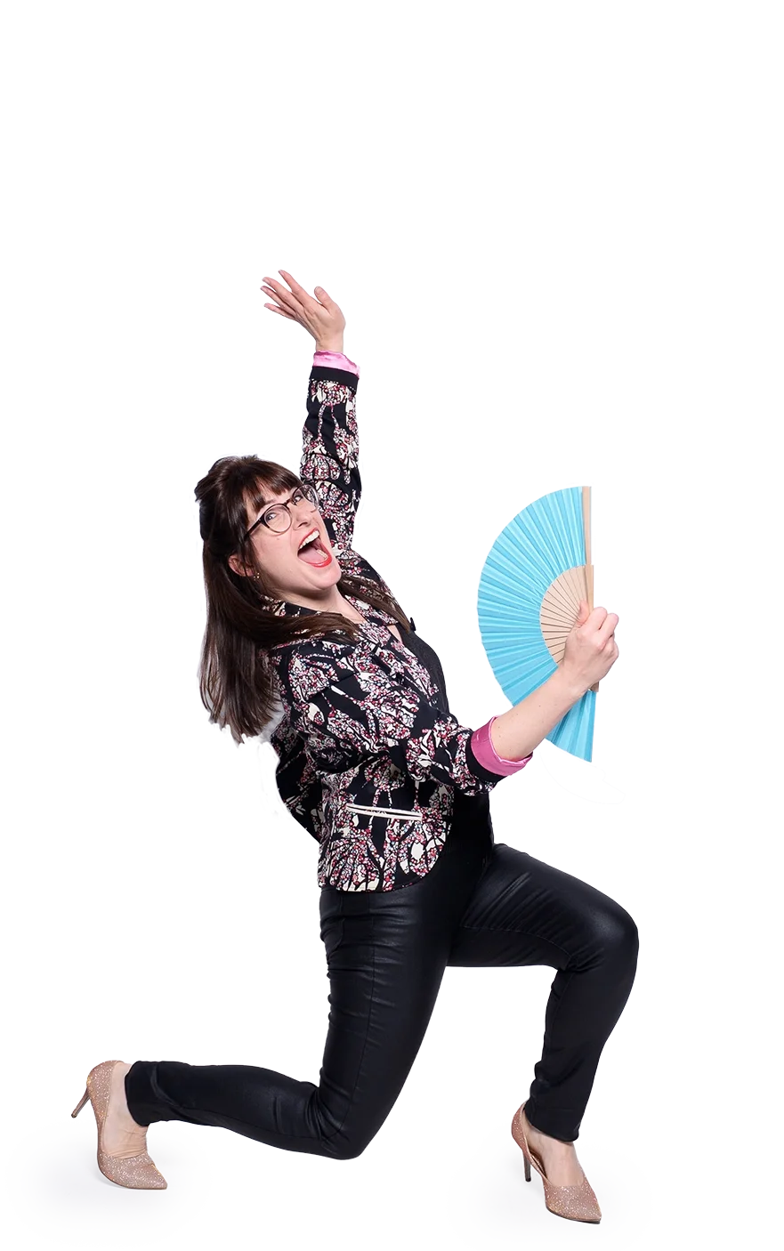 Eine fröhliche Frau als Überraschungsgast mit Brille, die auf einem Knie sitzt und eine Fächer hält, während sie nach oben zeigt.