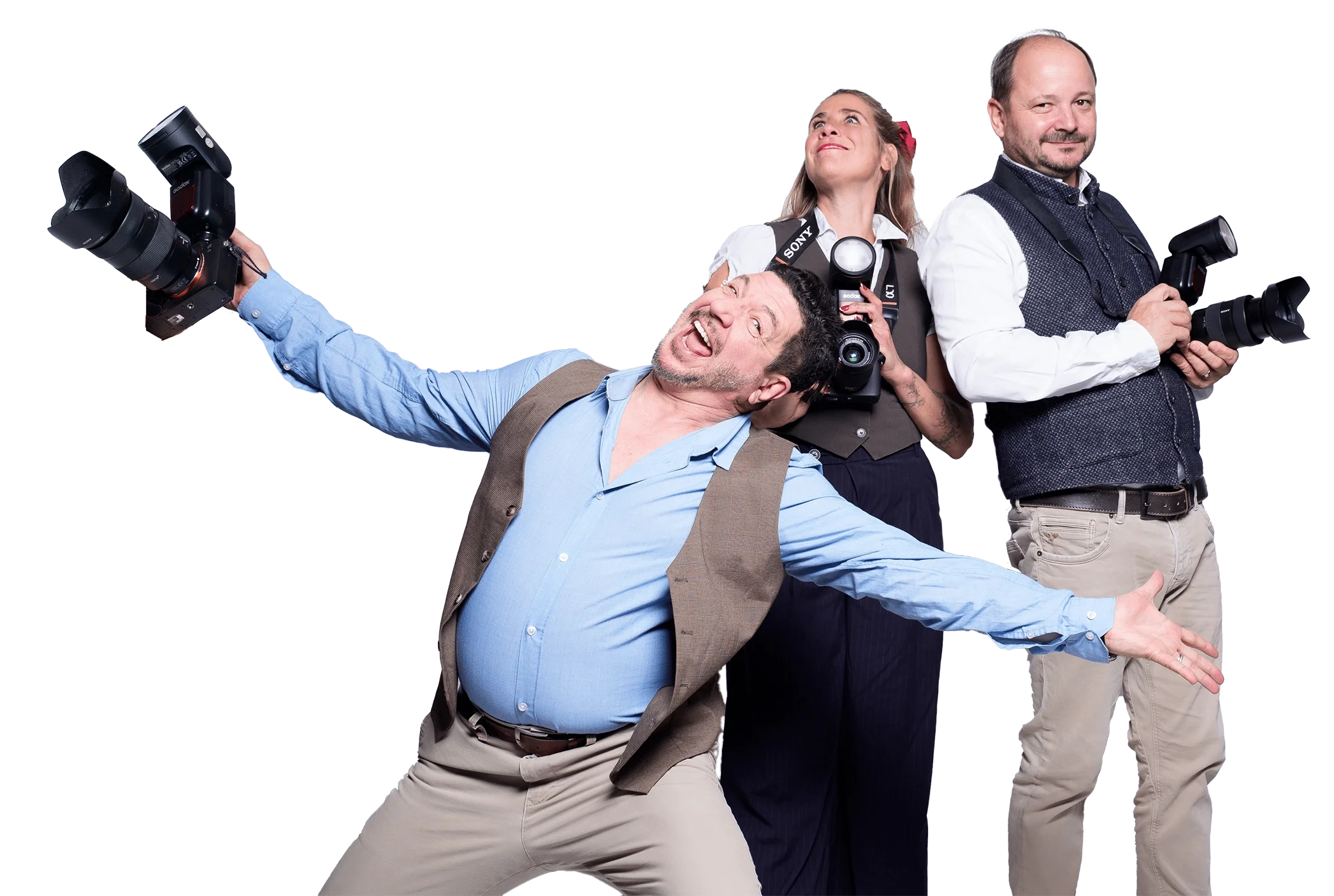 Drei Fotografen stehen mit Kameras, einer tanzt freudig, während die anderen konzentriert posieren.