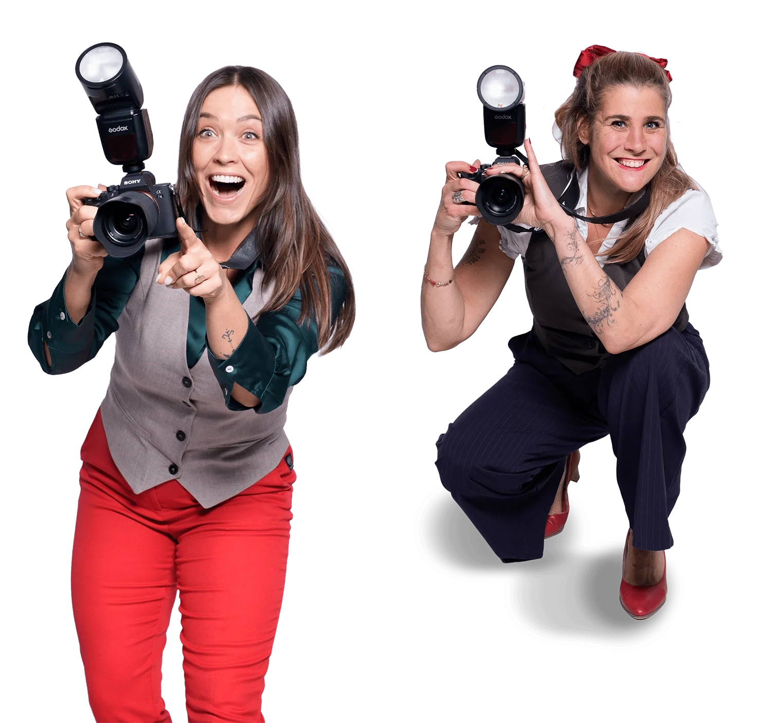 Zwei lachende Frauen mit Fotografen-Ausrüstung, eine in rot und grauem Outfit, die andere in dunkler Hose und weißen Oberteil, posieren mit Kameras auf einem weißen Hintergrund.