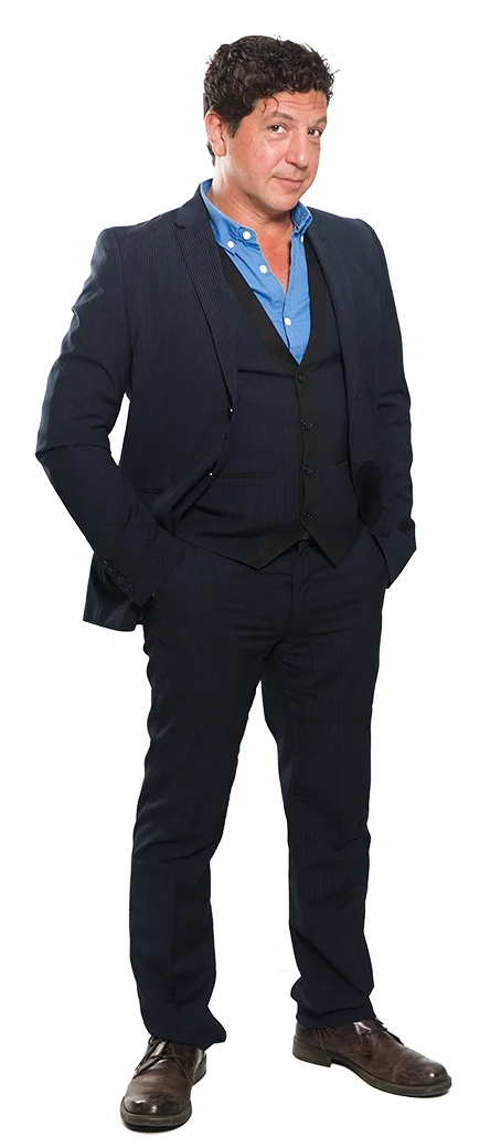 Ein komödiantischer Mann trägt einen dunkelblauen Anzug mit Krawatte und Hemd, steht mit den Händen in den Taschen, Selbstvertrauen und stilvolles Auftreten