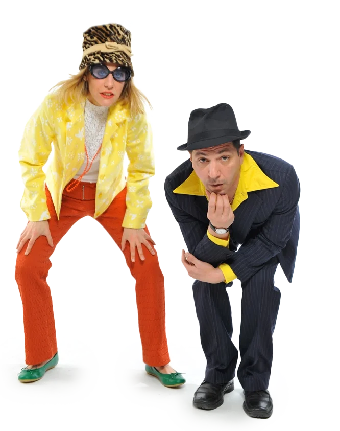 Zwei humorvolle Menschen, eine Frau und ein Mann, als Überraschungsgäste in bunten, auffälligen Kleidung und Accessoires, in einer komischen Pose.