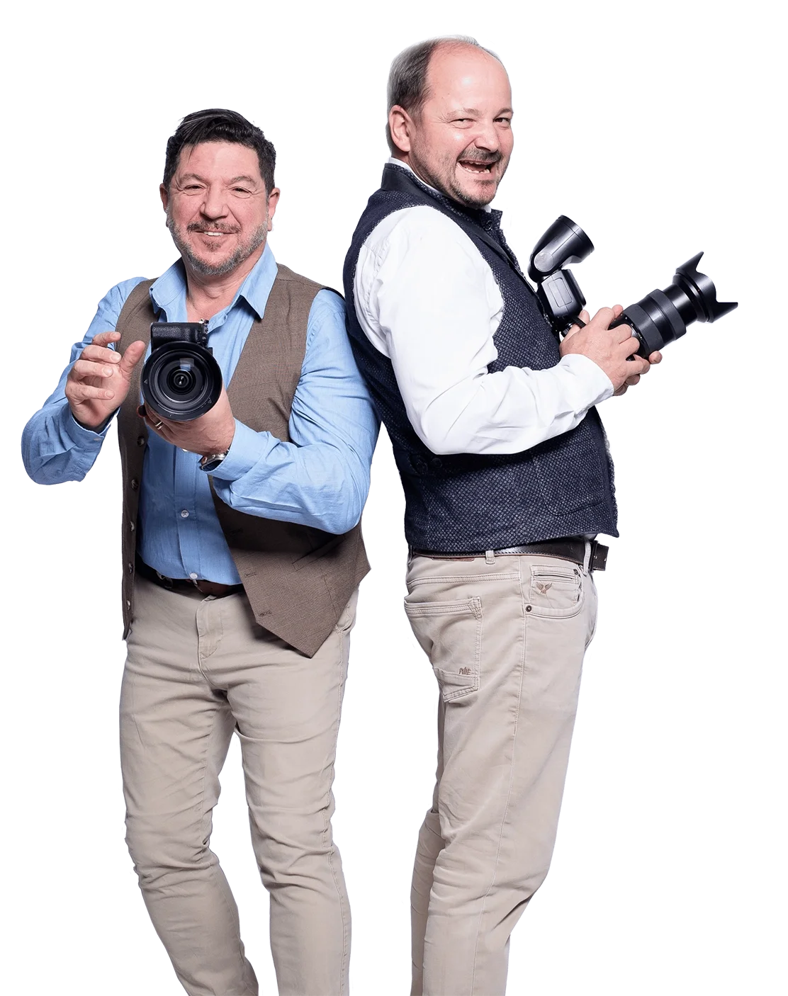Zwei Männer, die als Fotografen gekleidet sind, stehen nebeneinander mit Kameras. Der Mann auf der linken Seite trägt ein blaues Hemd und eine braune Weste, der Mann auf der rechten Seite trägt ein weißes Hemd und eine dunkle Weste. Beide lachen und 