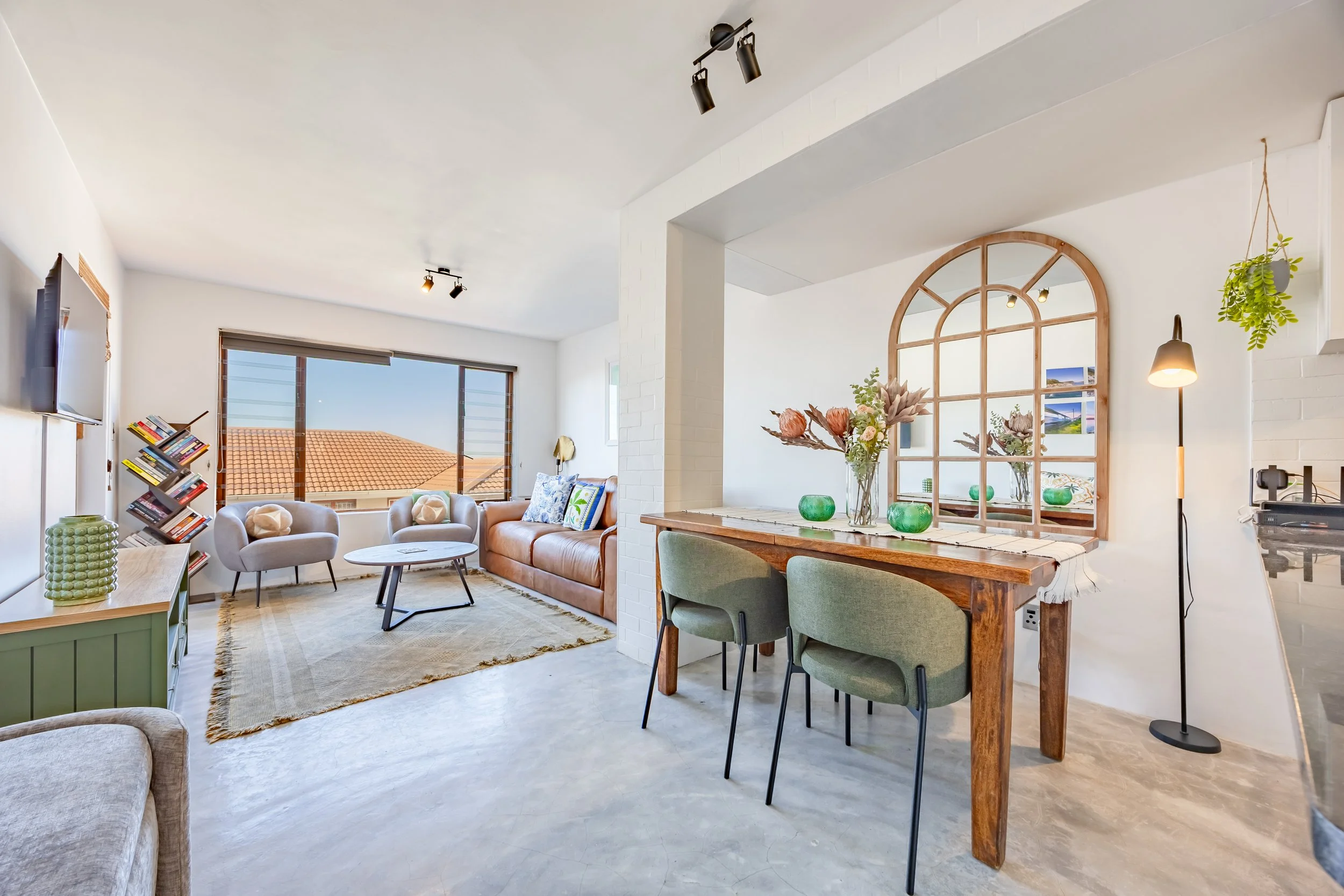 Bright open-plan living and dining area at a Kalk Bay holiday apartment, showcasing coastal interiors, natural light and views towards the surrounding neighbourhood.