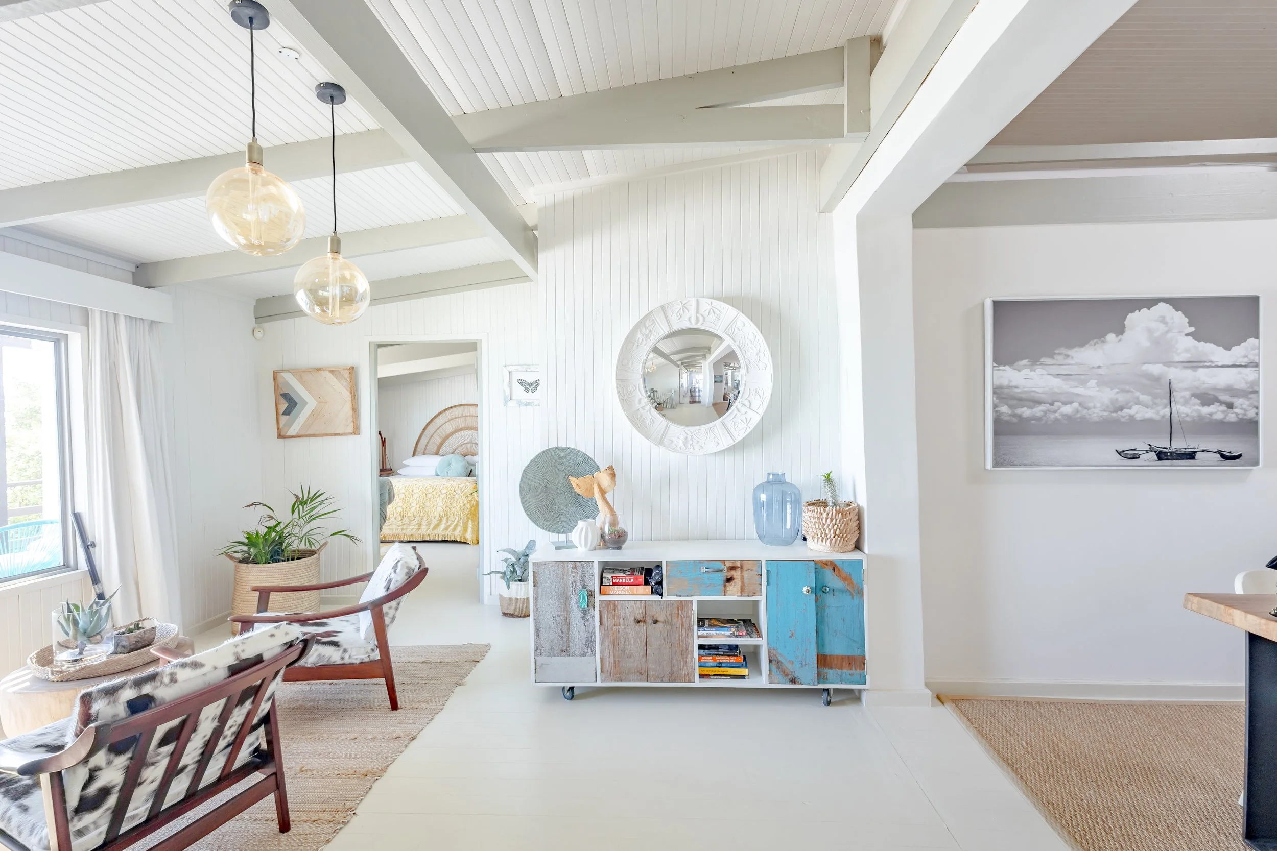 Modern coastal entryway with white vaulted ceilings, a sunburst mirror, and a colorful upcycled sideboard.