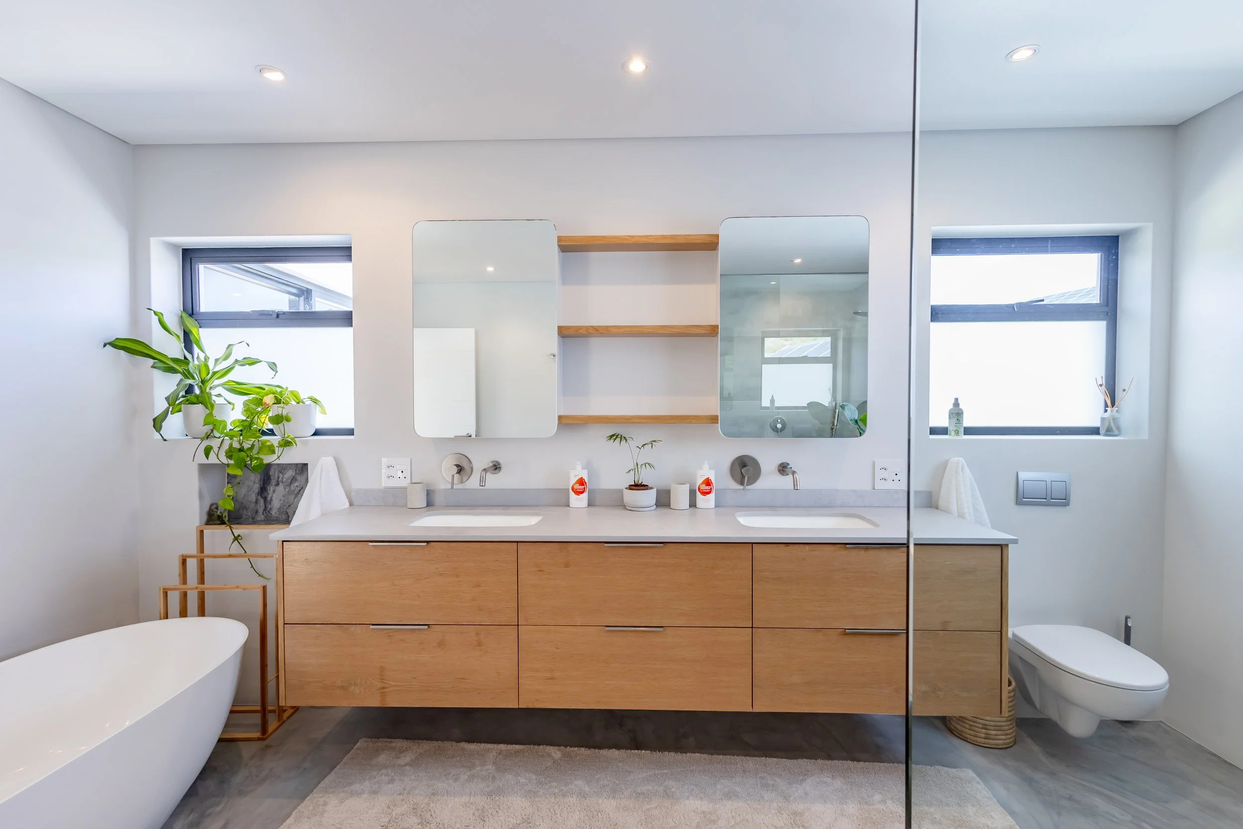 High-end bathroom photography in Clifton featuring a double wooden vanity, modern mirrors, and clean white finishes.
