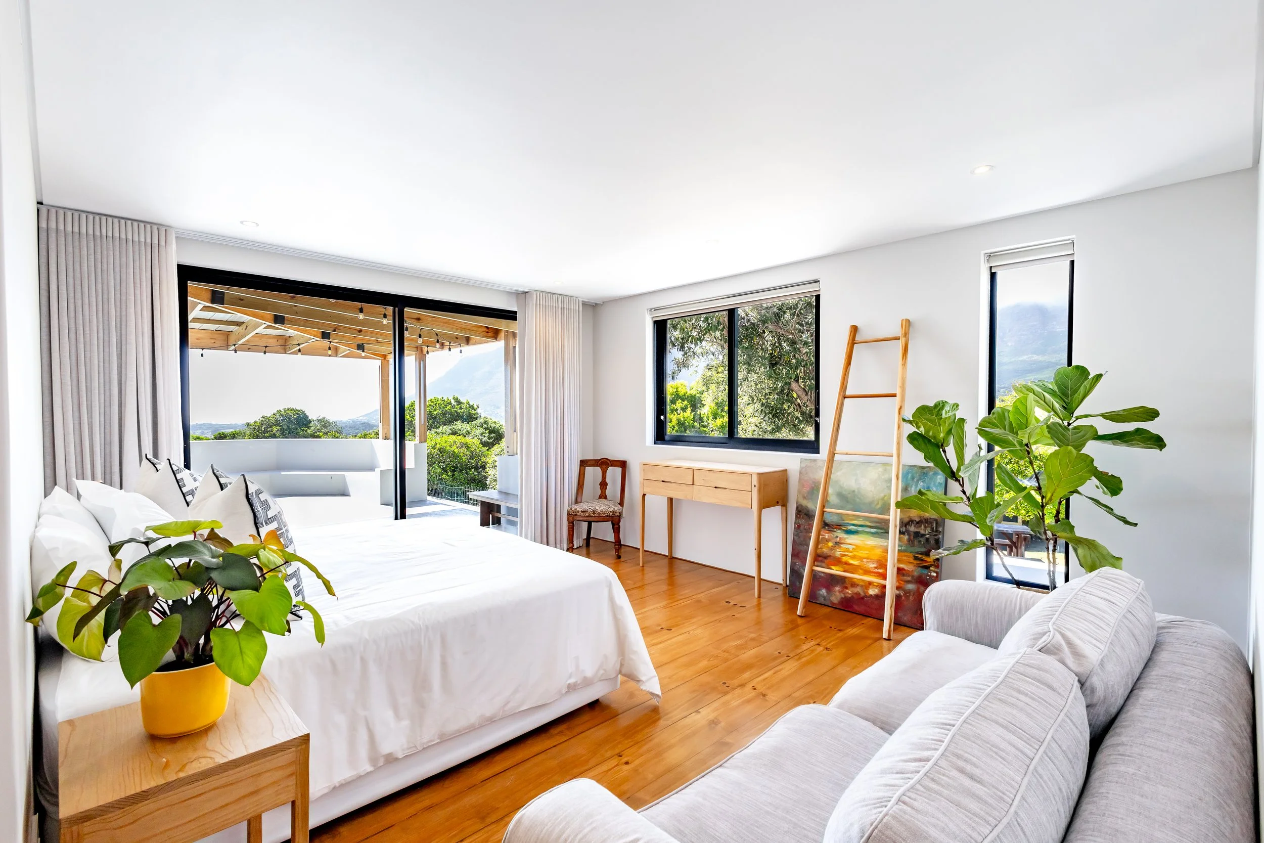 Spacious master suite in a Camps Bay luxury rental showing a king-size bed and large windows with mountain views.