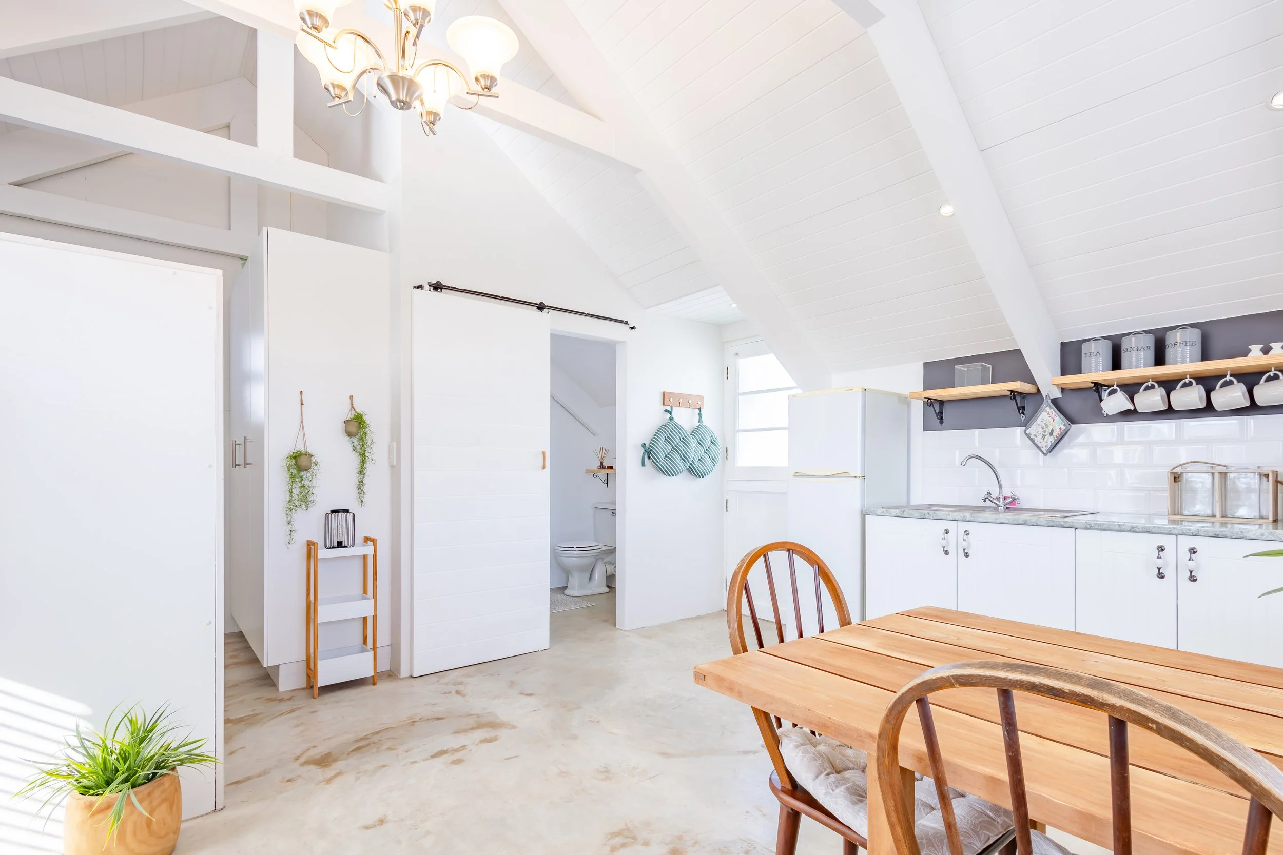Architectural interior photography of a Cape Town studio showing a sliding barn door and clean, modern layout with high ceilings.